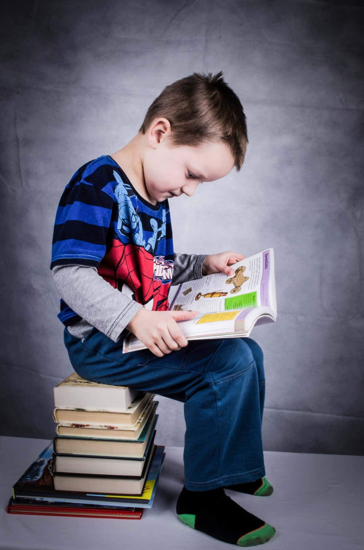Young Smart Boy Sitting On Books Picture