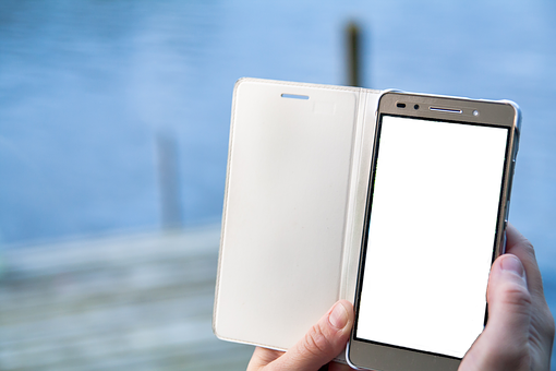 Smartphonewith Open Flip Case PNG — A hand holds a white flip phone case with a black screen displaying code against a blurred blue water background.