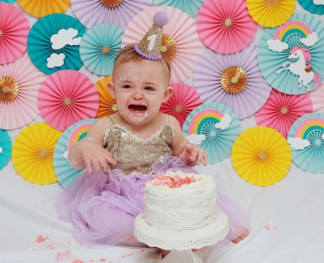A Baby Girl In A Unicorn Costume Eating Cake