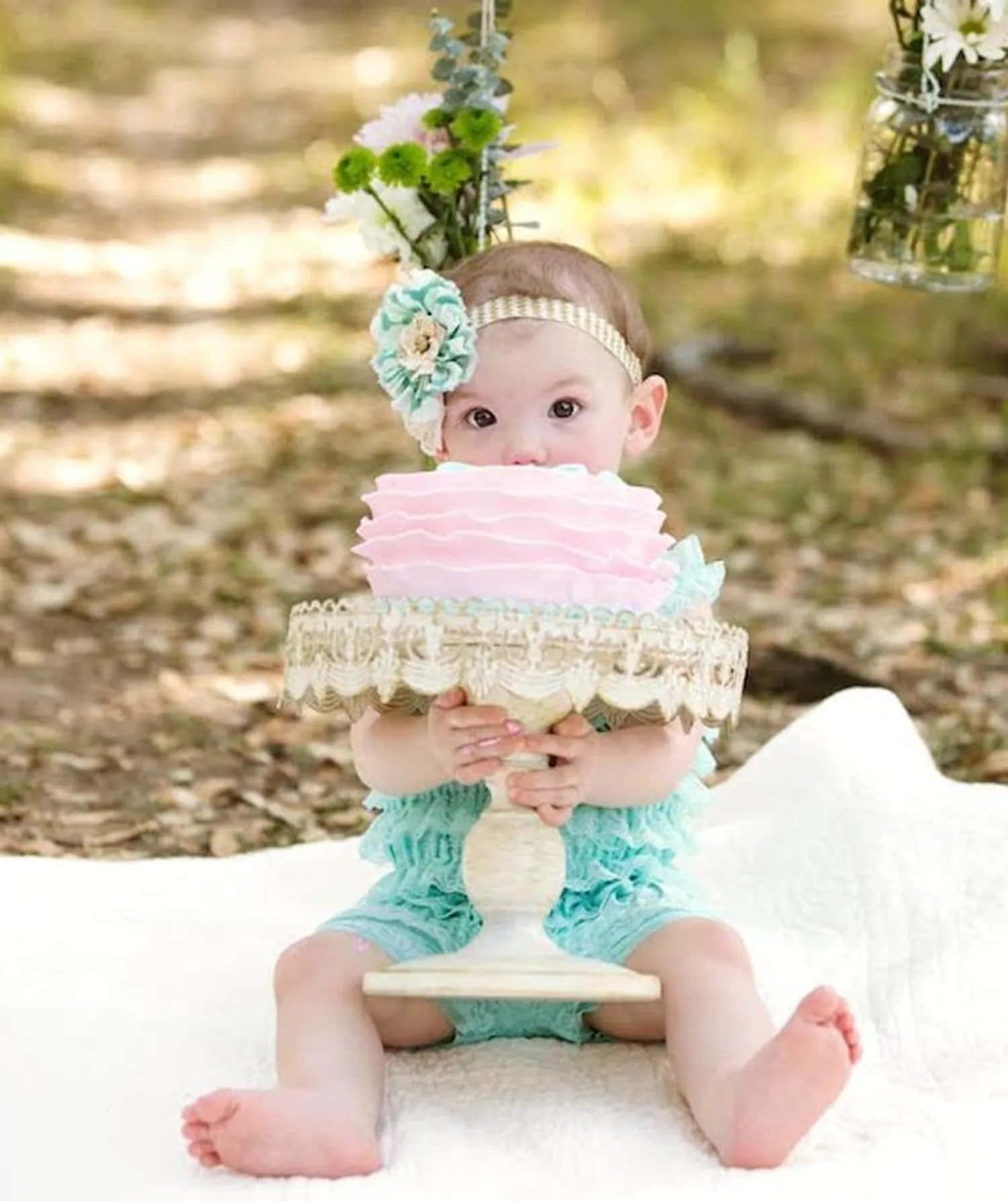 A Baby Girl Sitting On A Blanket With A Cake