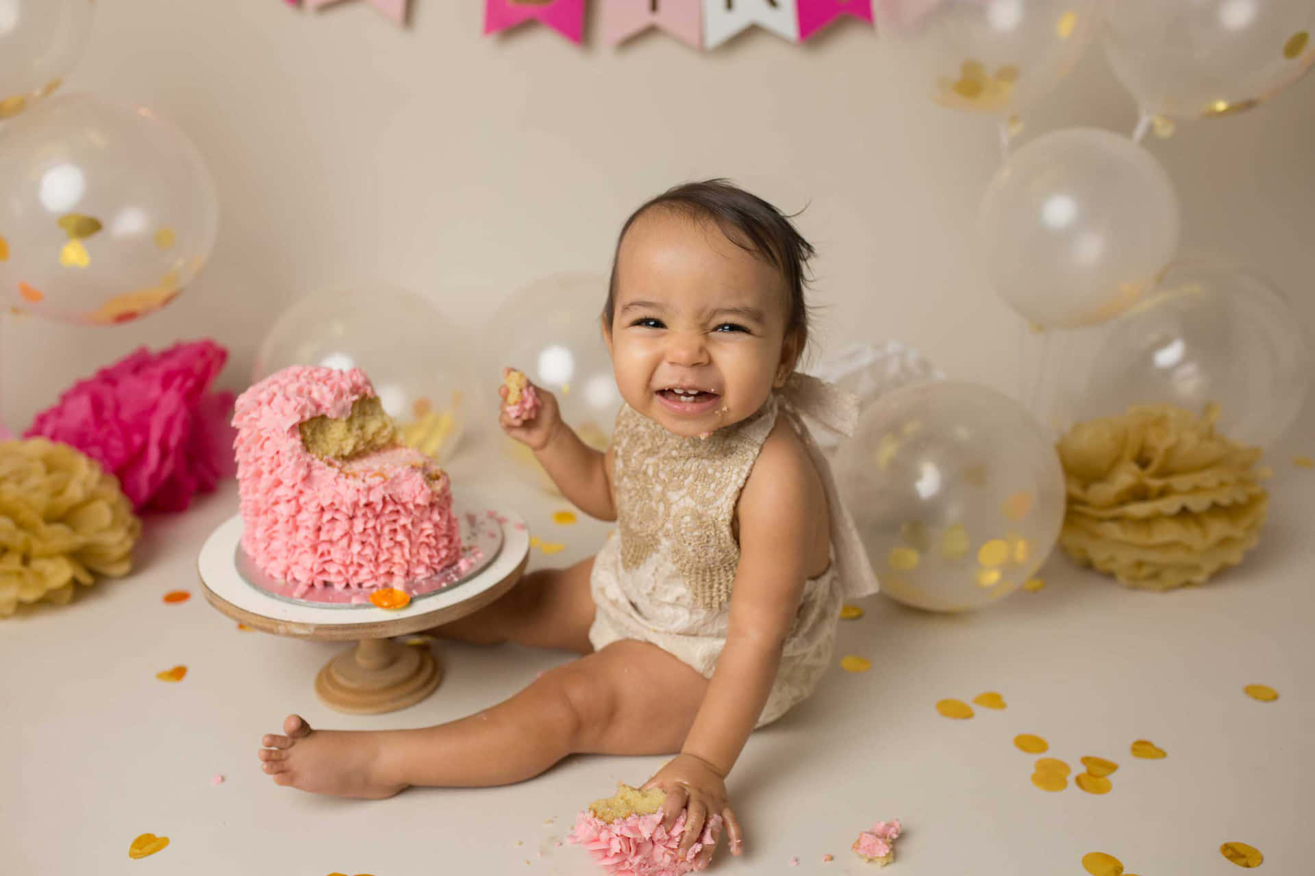 A Baby Girl Sitting In Front Of A Cake With Balloons