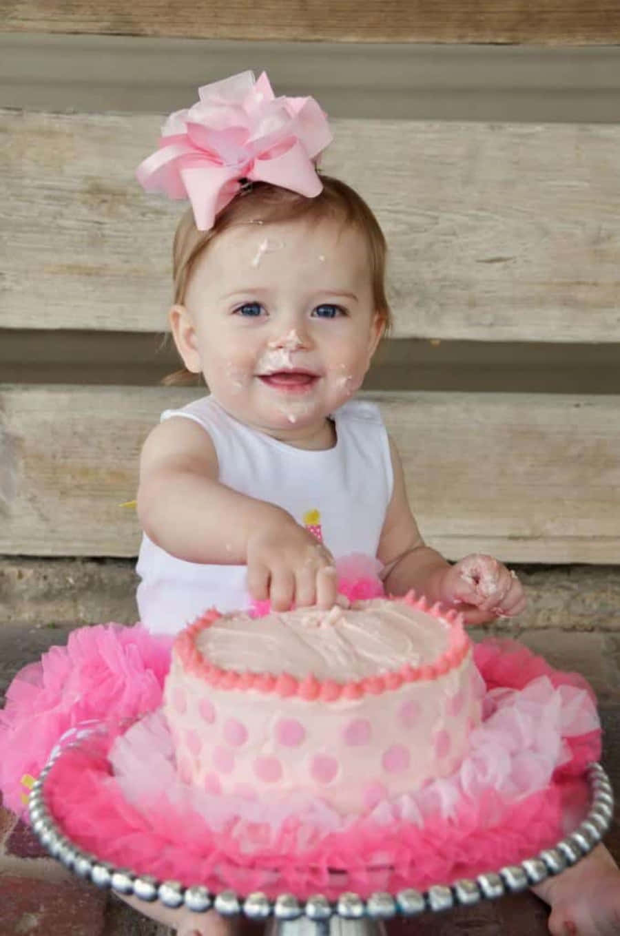 A Baby Girl In Pink Tutu Is Eating A Cake