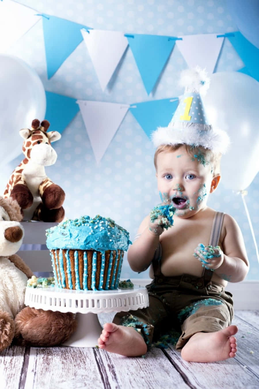 A Baby Boy Is Sitting In Front Of A Cake And Cupcake