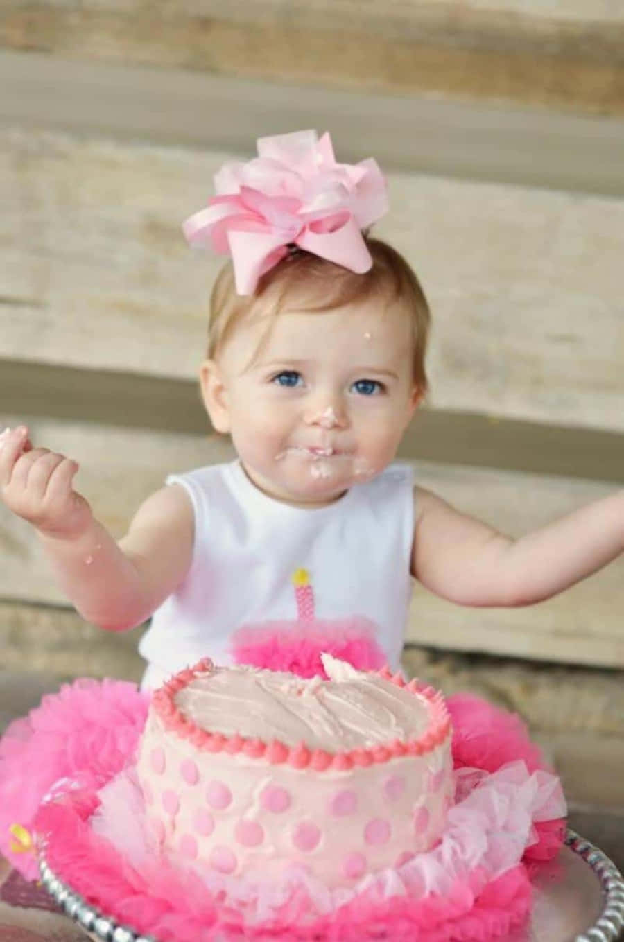 A Baby Girl Is Holding A Pink Cake