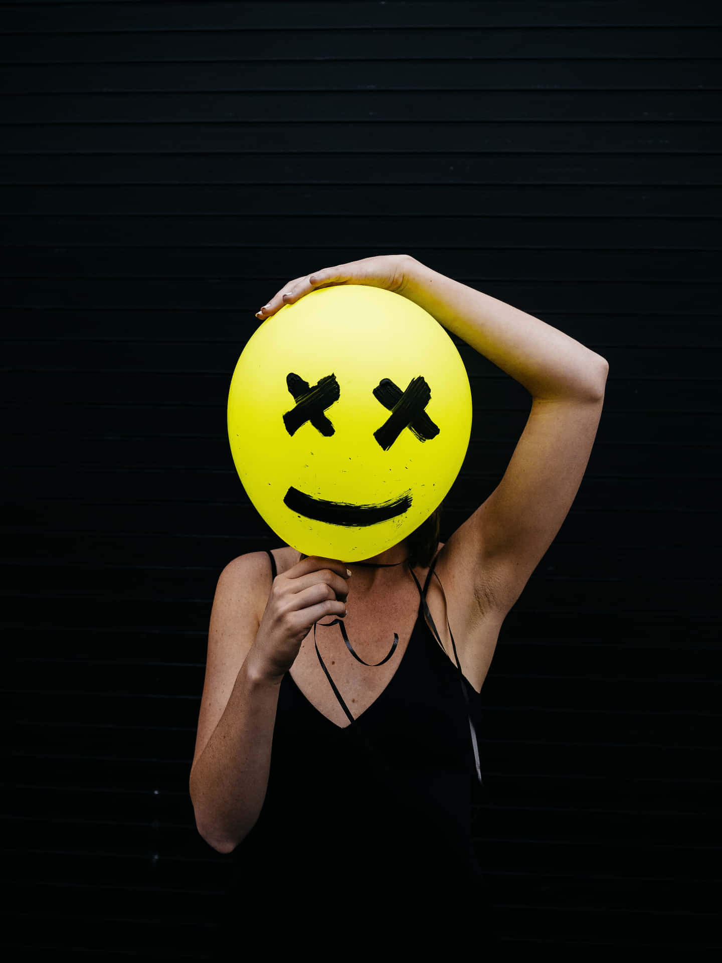 Woman Holding A Yellow Smiley Face Mask