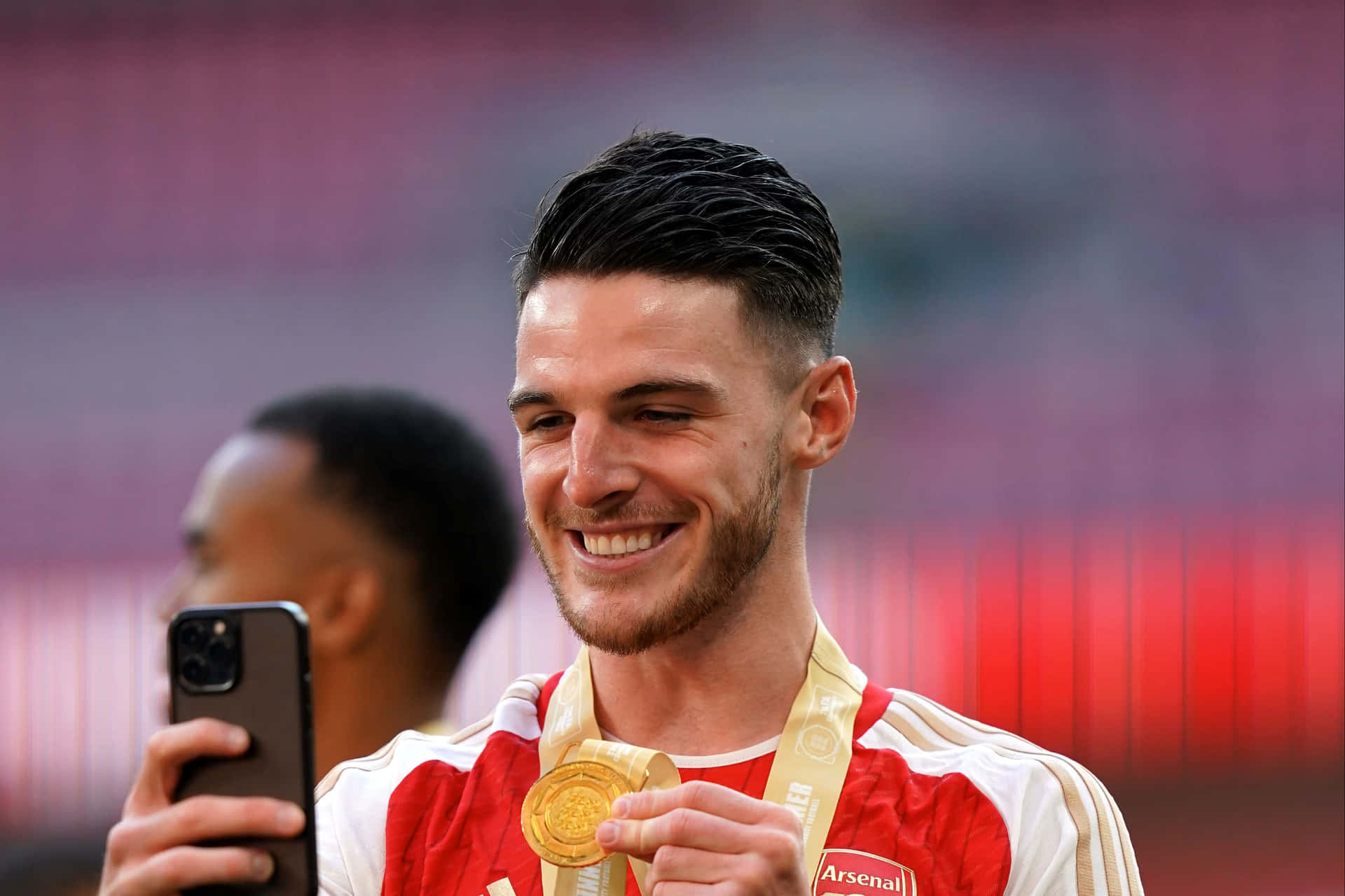 Smiling Athletewith Gold Medaland Smartphone Wallpaper