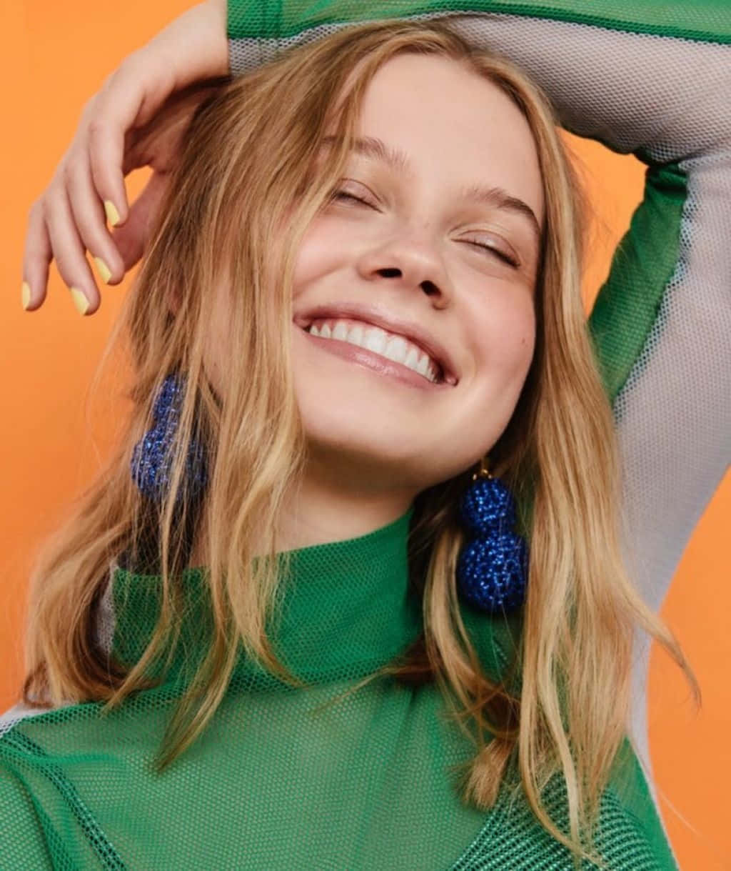 Smiling Blonde Woman Green Top Blue Earrings Wallpaper