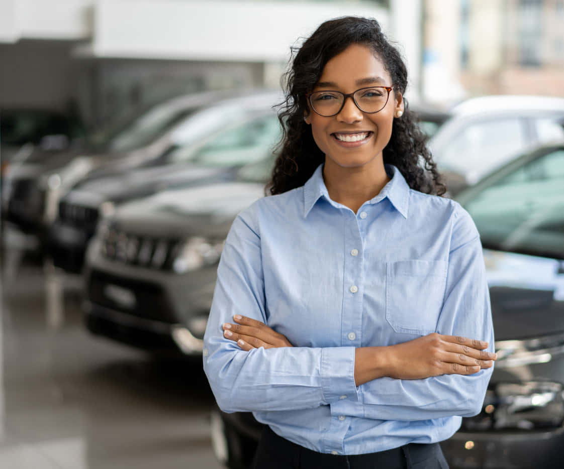 Sonrientejoven Mujer Negra Vendedora De Autos En Concesionario. Fondo de pantalla