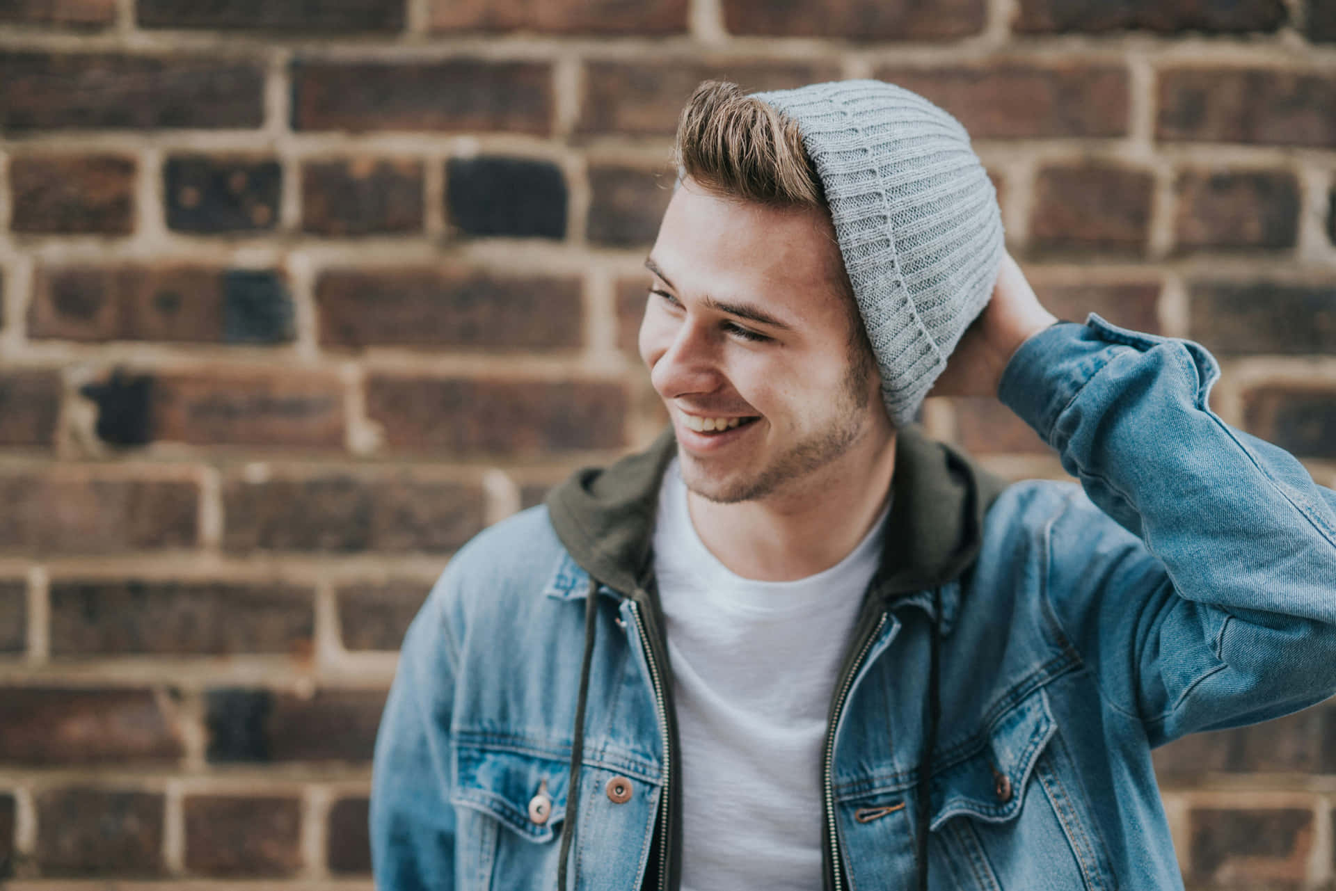 Smiling Young Man Beanie Brick Wall Wallpaper