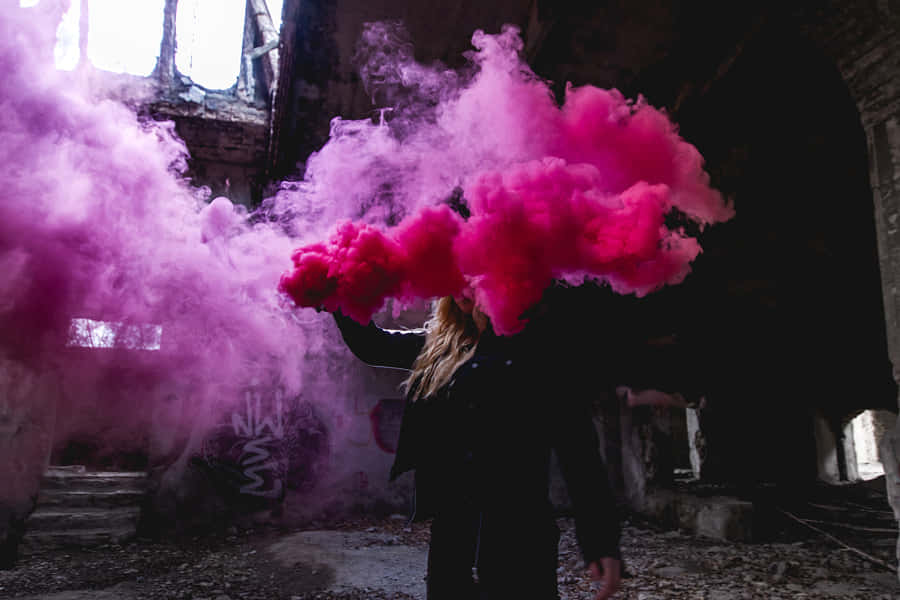 A Woman Is Holding Pink Smoke In An Abandoned Building