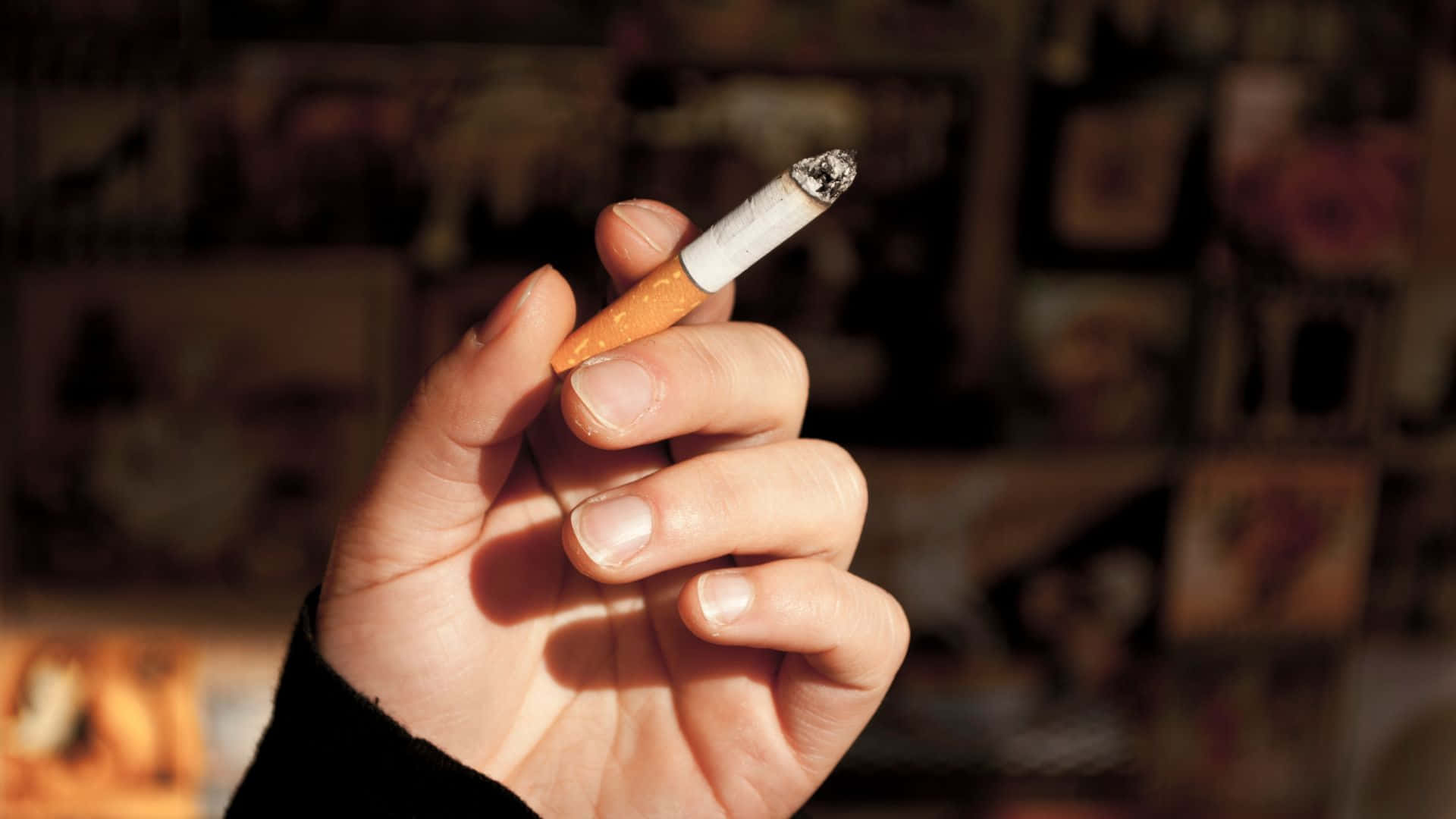 Enperson Holder En Cigaret Foran Et Billede.