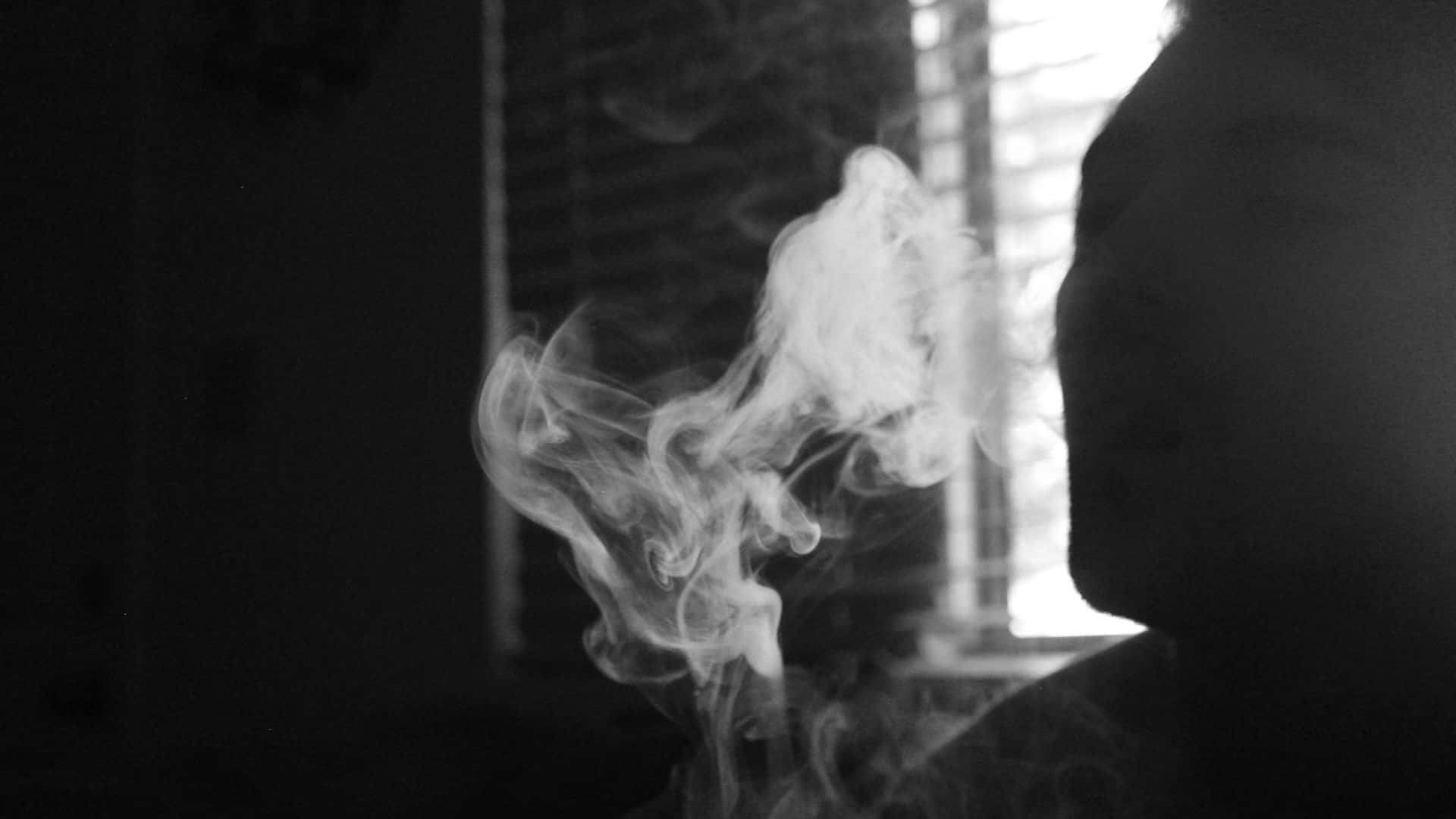 A Man Smoking A Cigarette In The Dark