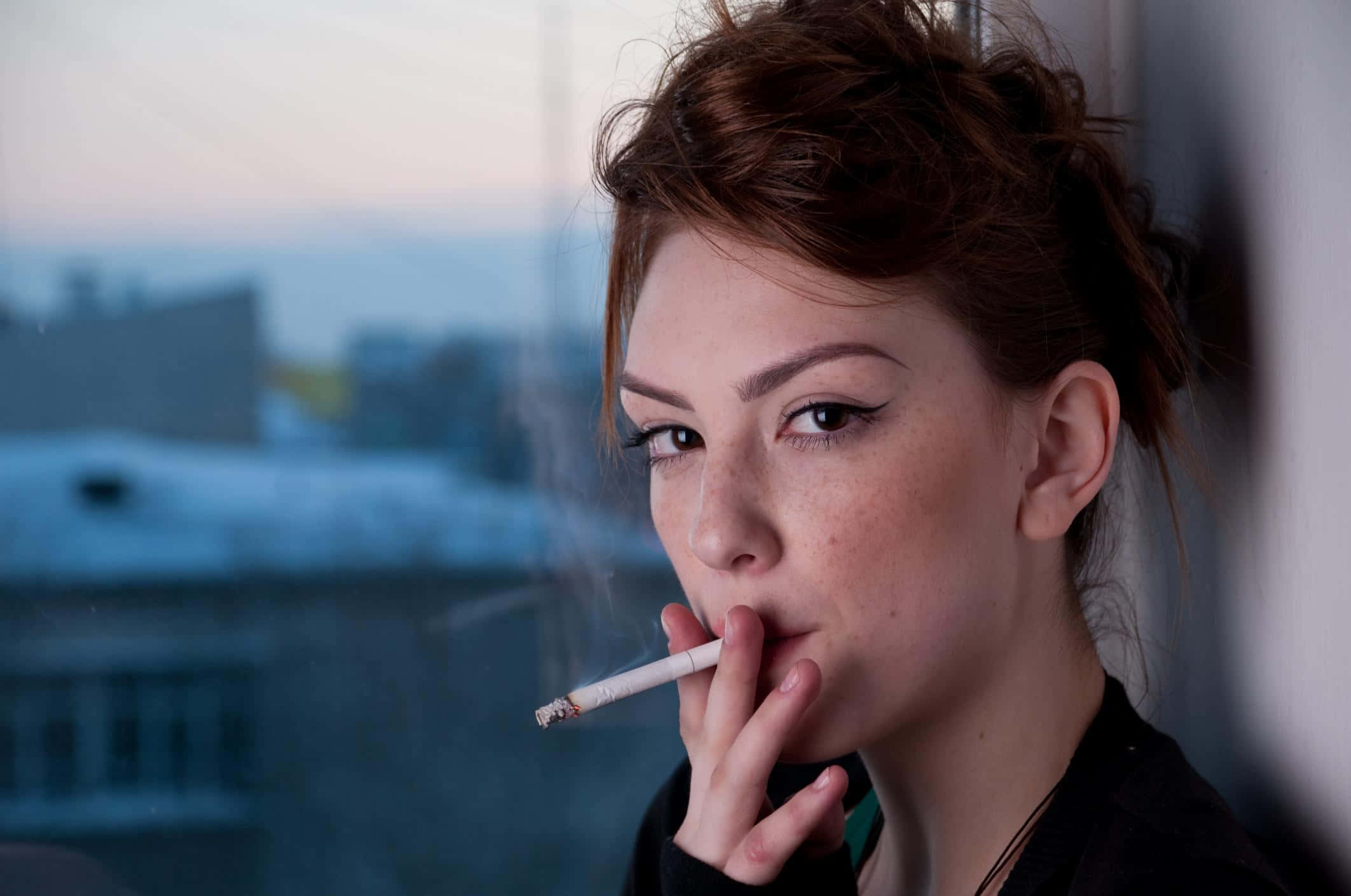 A woman smoking a cigarette on a rooftop