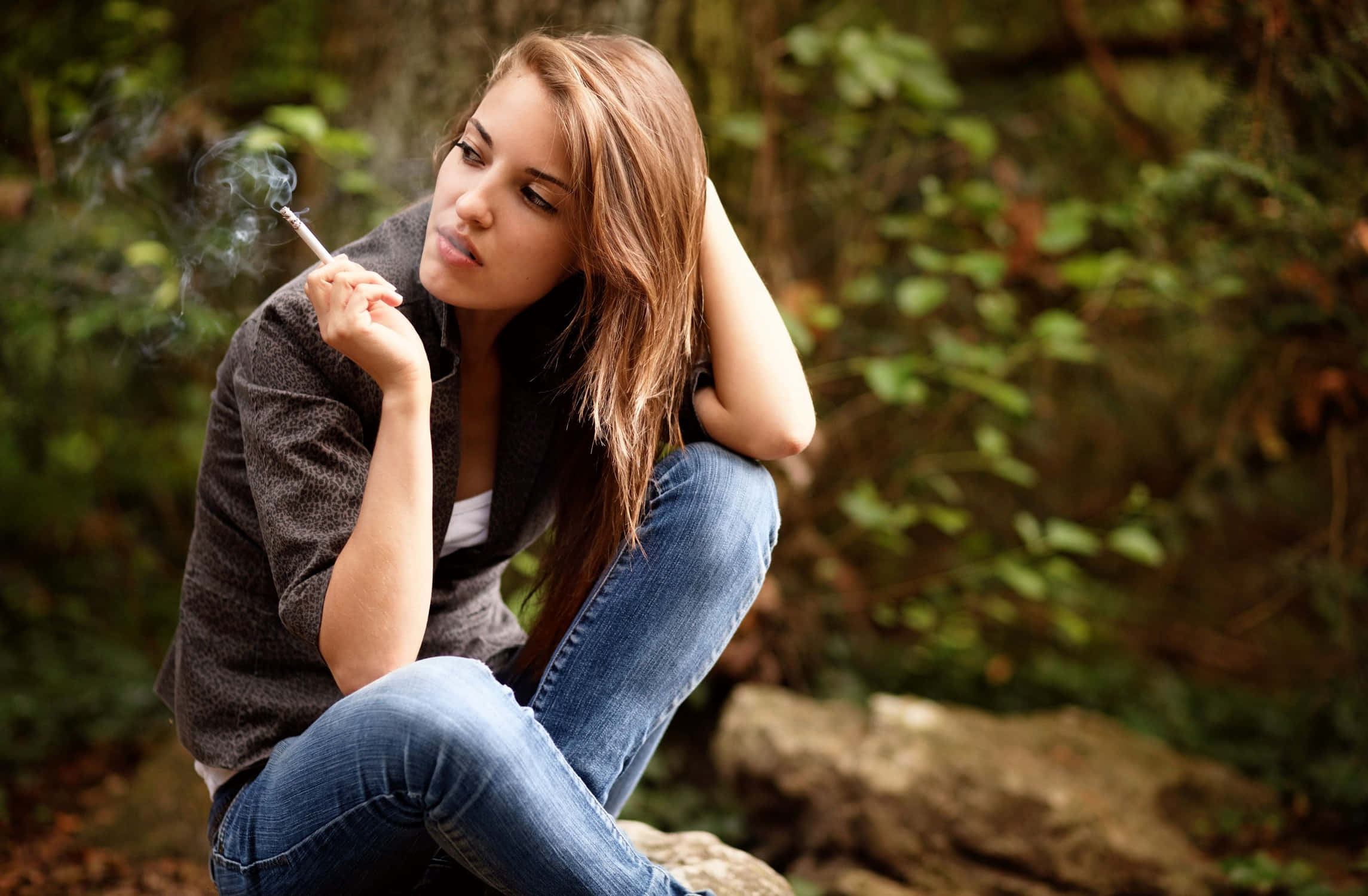 A Woman Sitting On A Rock Smoking A Cigarette