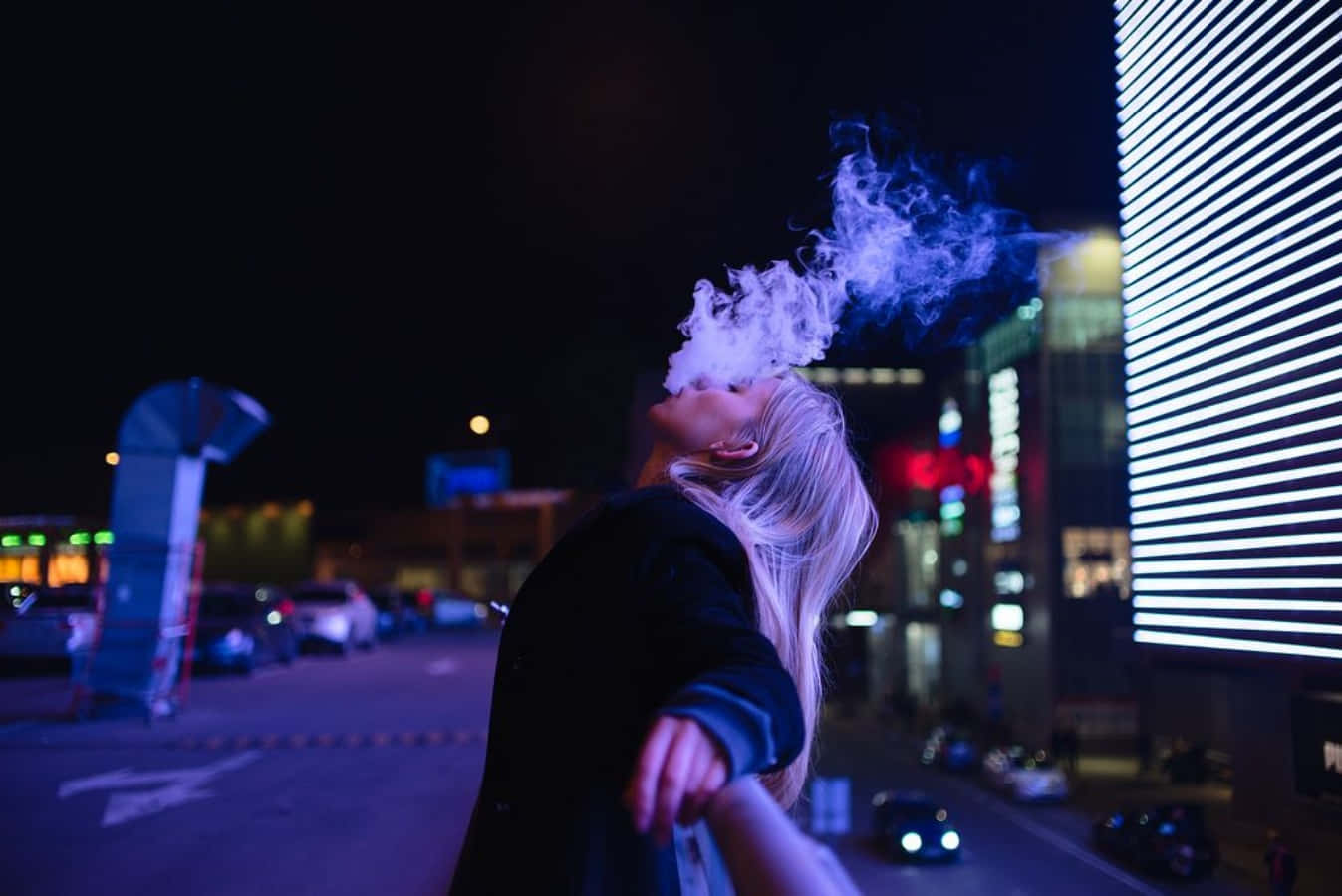 A Woman Smoking A Cigarette In The City At Night