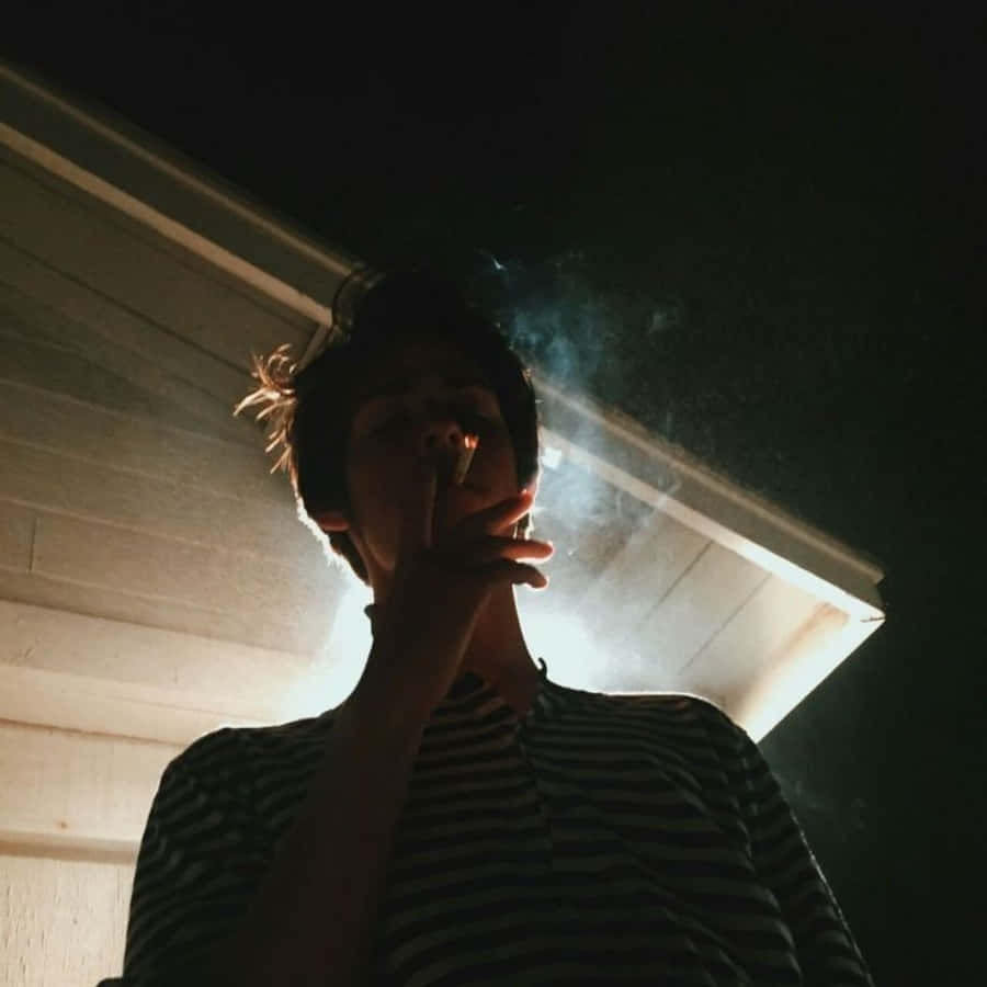 A Man Smoking A Cigarette In Front Of A House