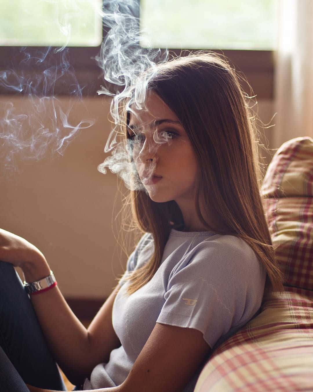 A Girl Sitting On A Couch Smoking A Cigarette