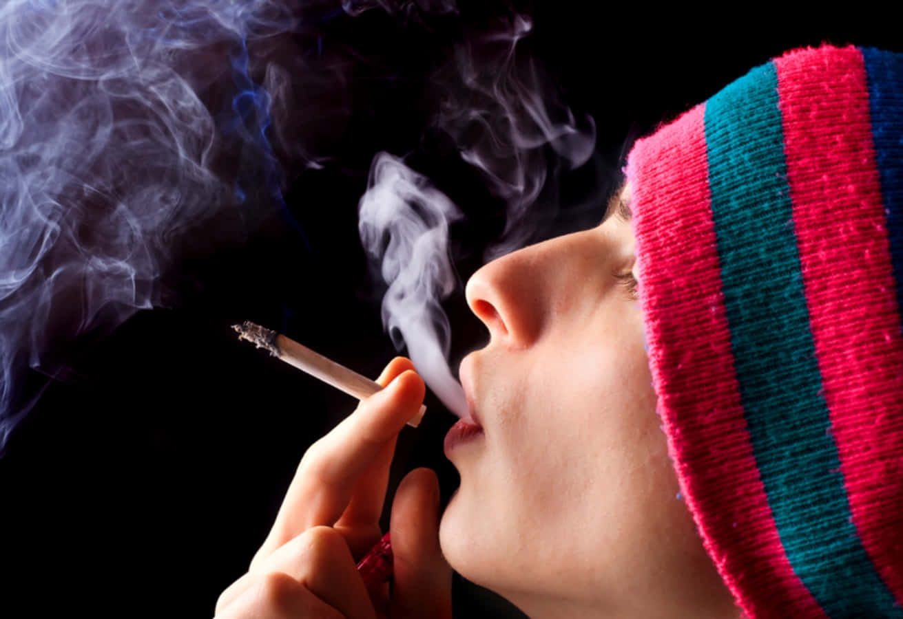 A Woman Smoking A Cigarette In A Hat