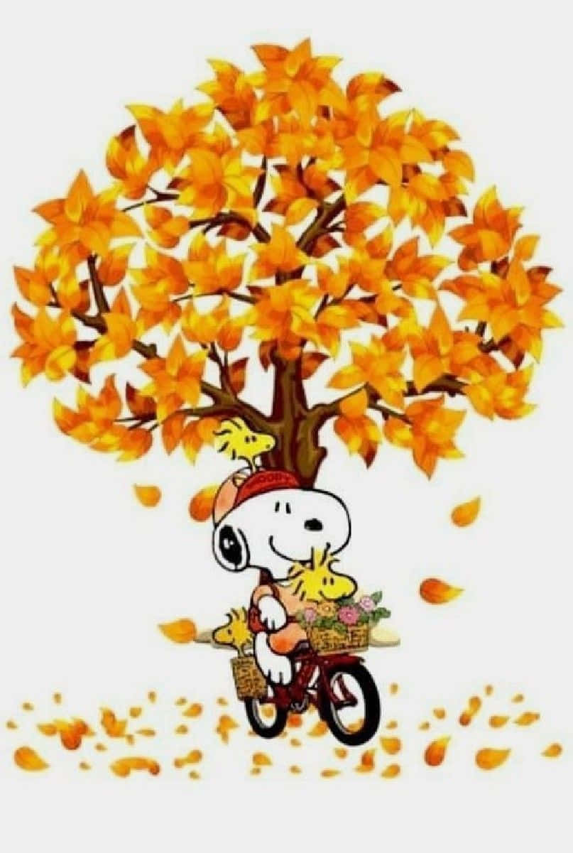 Snoopy falls delightedly into a pile of yellow leaves Wallpaper