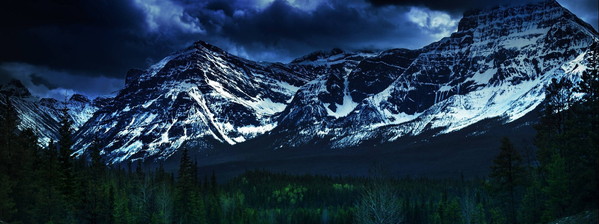 Snow-Capped Peaks Peeking Through A Majestic Forest Wallpaper