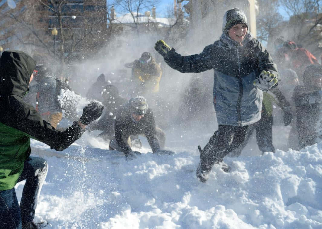 Friends Enjoying a Snowball Fight on a Winter Day Wallpaper
