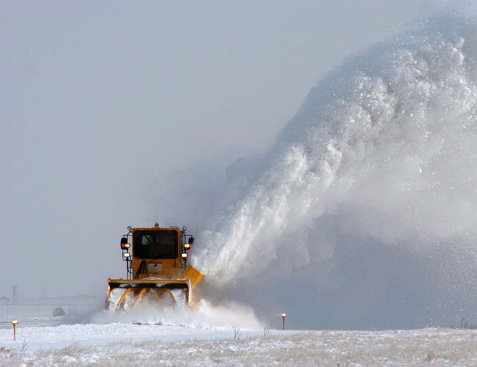 Heavy-duty snowplow clearing a snowy road Wallpaper
