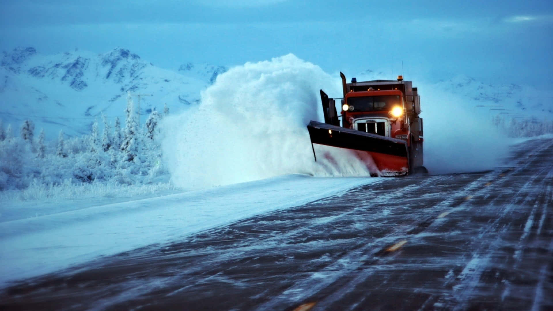 Snowplow clearing snow-filled road in winter Wallpaper