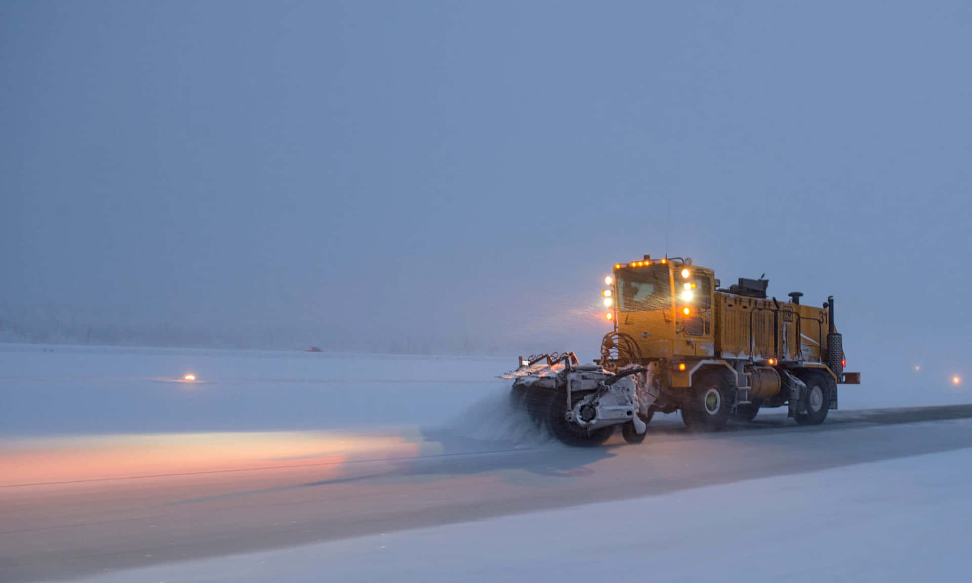 Powerful Snowplow Clearing a Snow-Covered Road Wallpaper