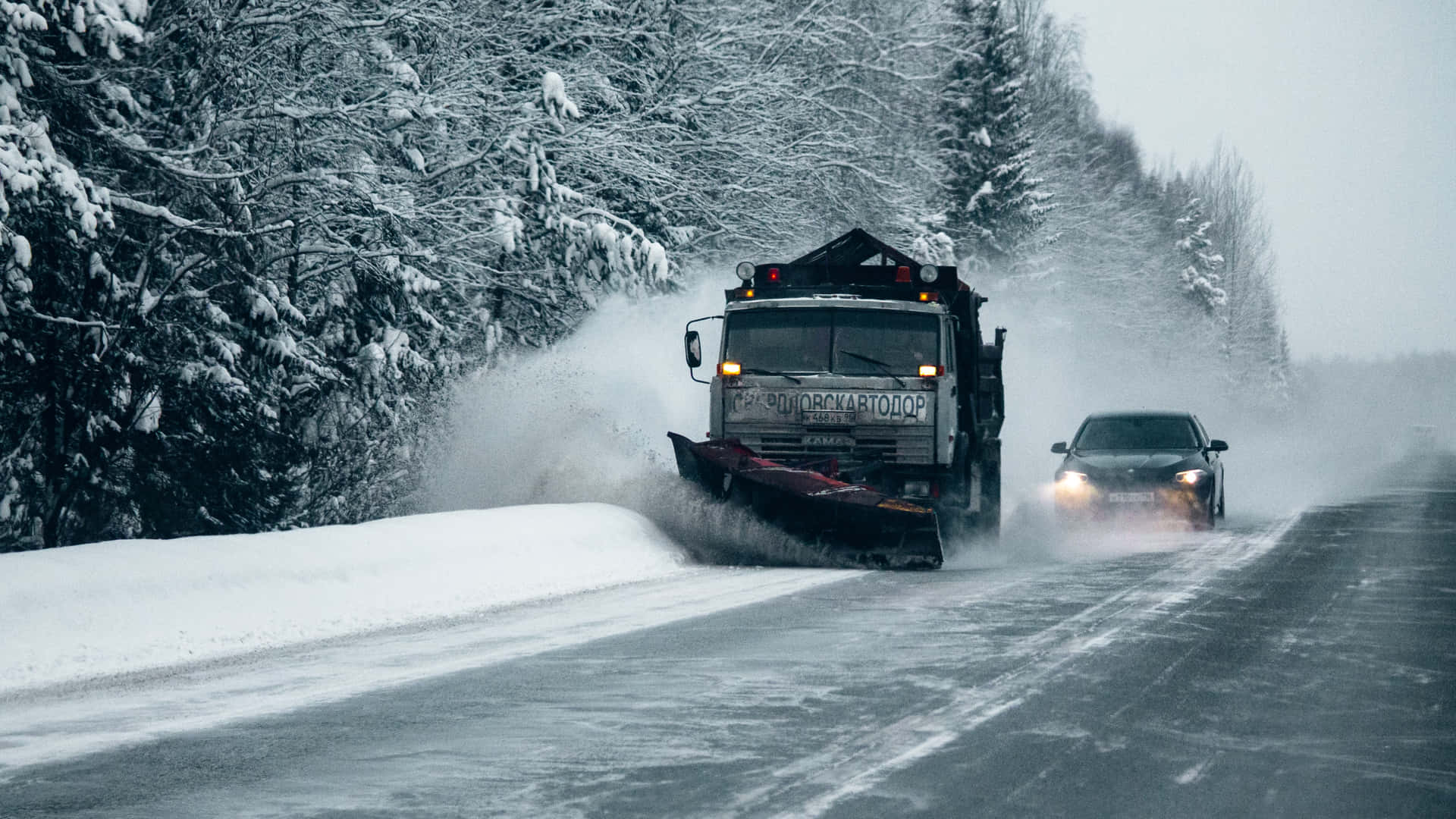 Powerful Snowplow Clearing Snow on a Mountain Road Wallpaper