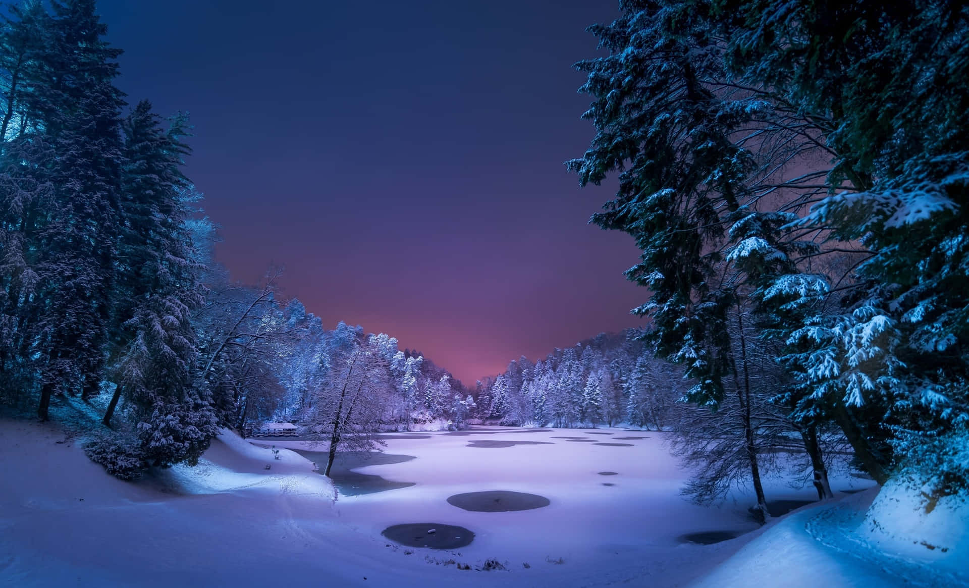 a snow covered lake at night with trees and snow