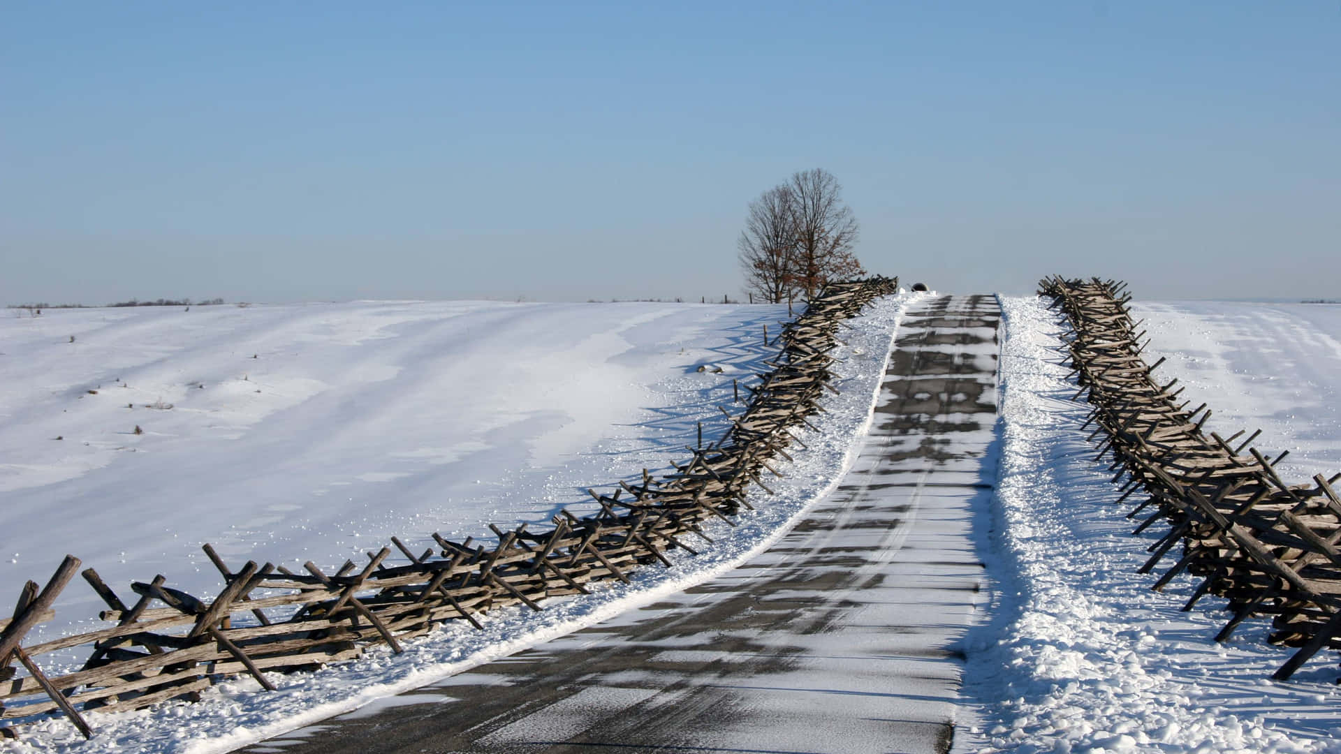 A tranquil snowy road through a serene winter landscape Wallpaper