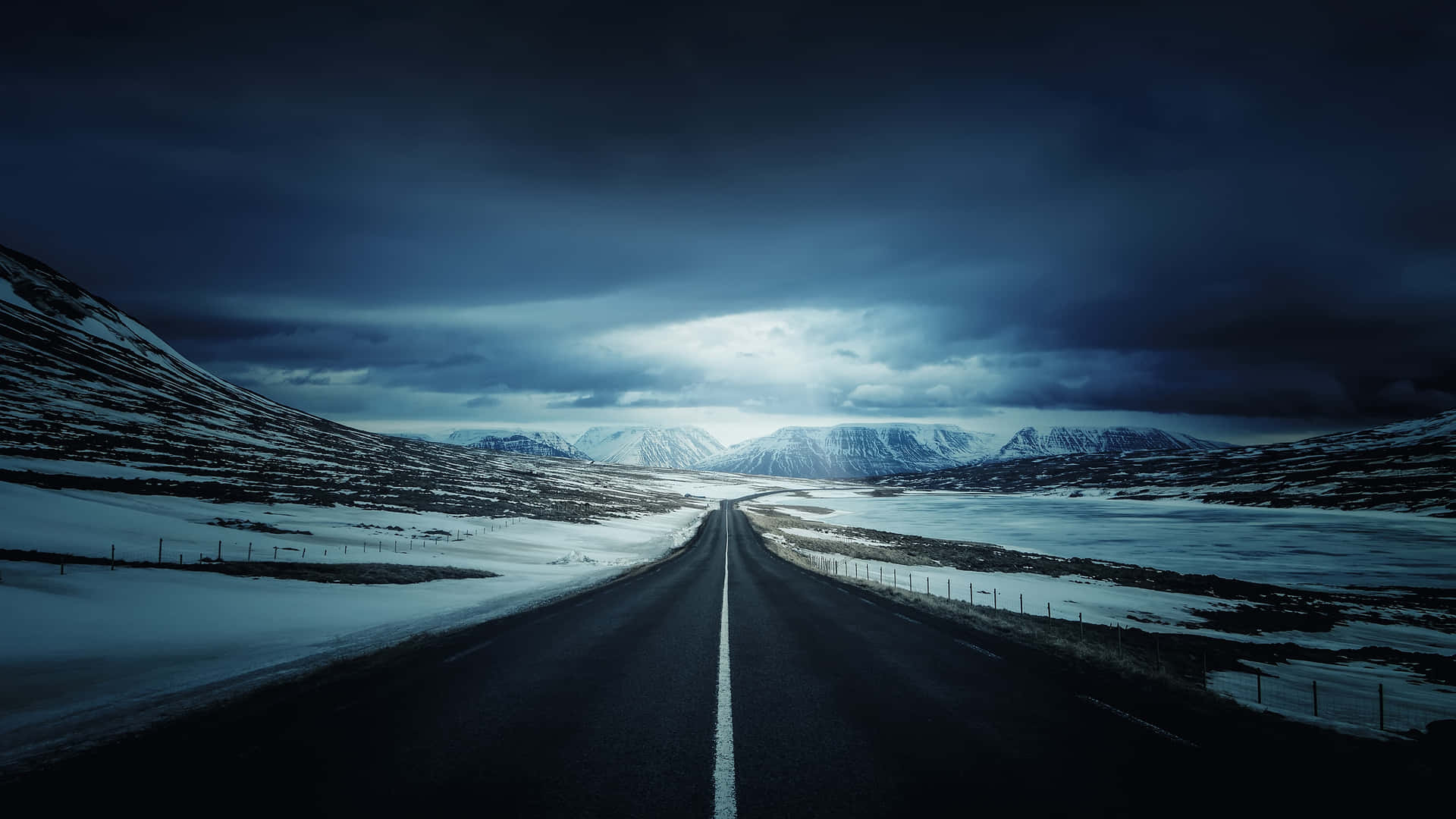 A snowy road amidst the serene winter landscape Wallpaper