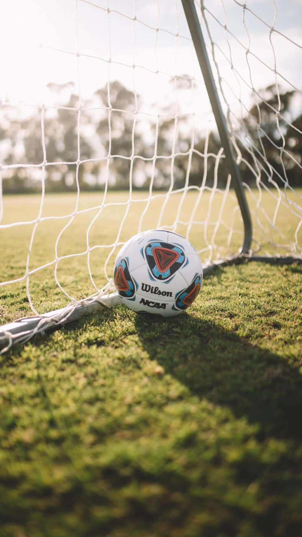 Soccer Ball In Net Sunlit Field Wallpaper