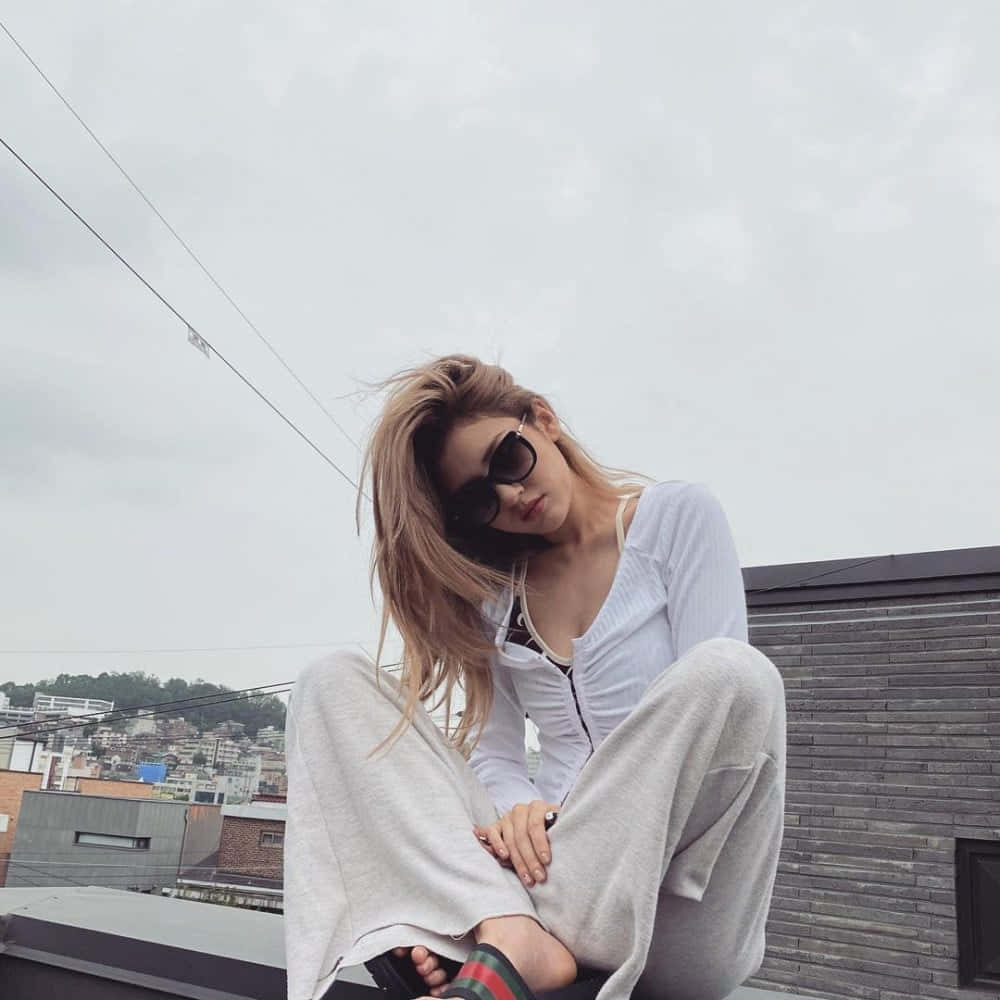 A Woman Sitting On A Roof With Sunglasses