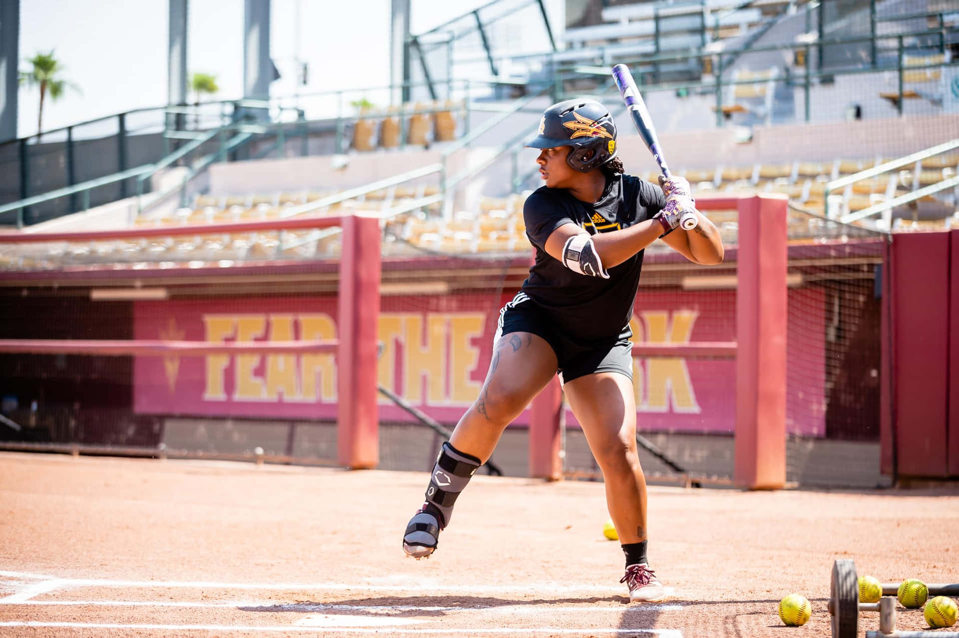 A Softball Player Swinging Her Bat At A Ball