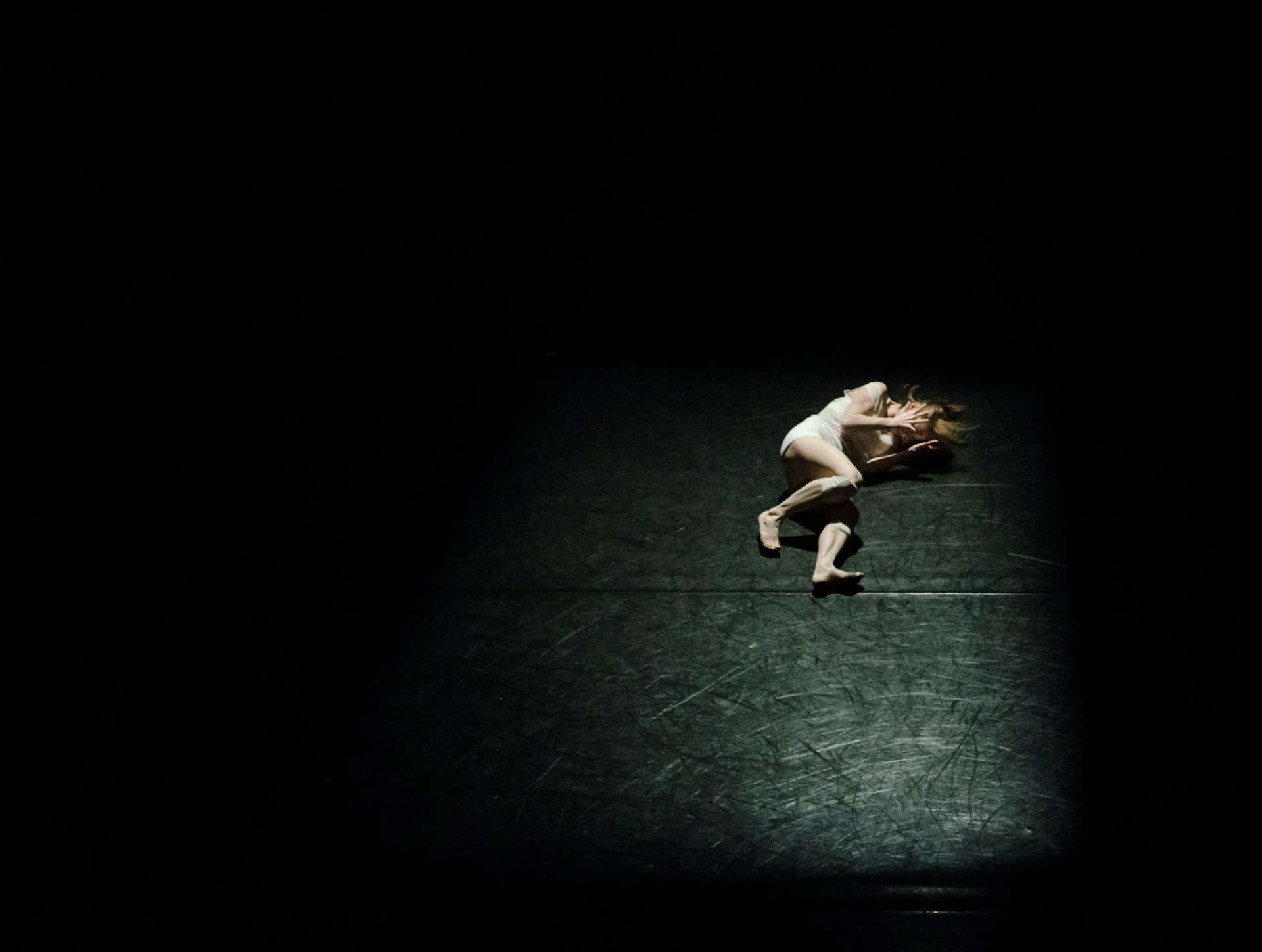 Solitary Dancer Spotlighted Darkness Wallpaper