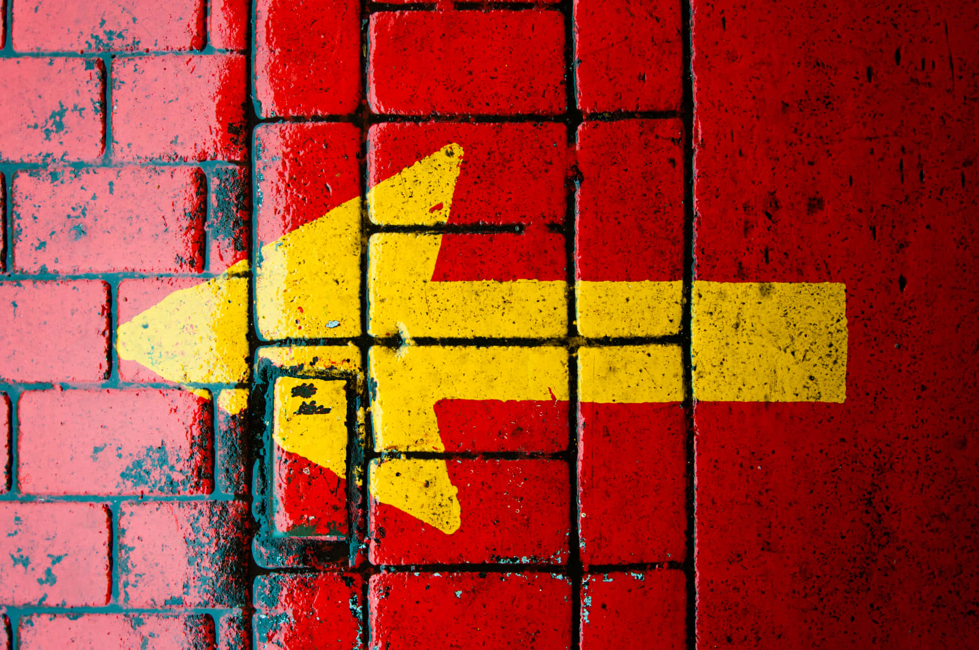 A Yellow Arrow On A Red Brick Wall