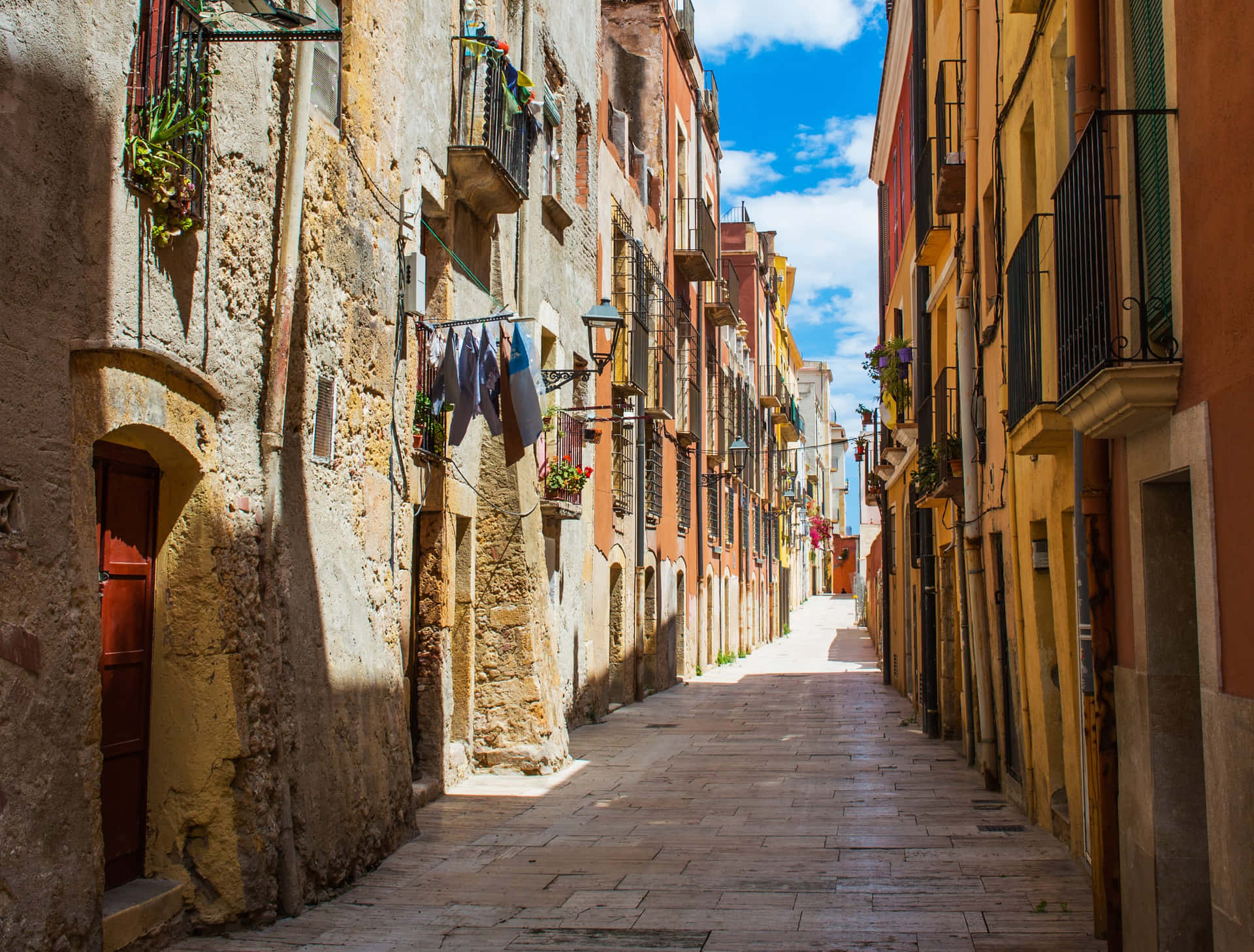 A Narrow Street With Buildings And A Laundry Line Wallpaper