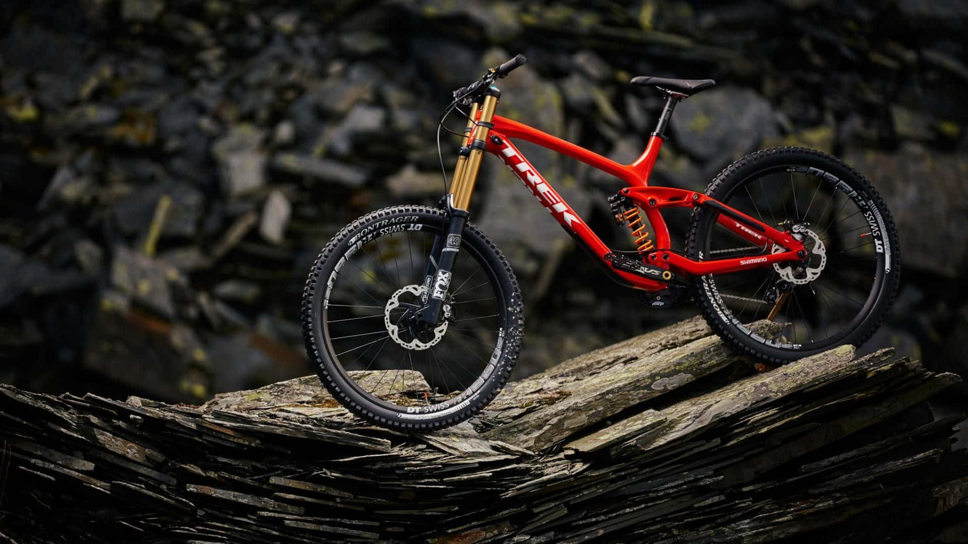 A Red Mountain Bike Is Sitting On Top Of Rocks Wallpaper
