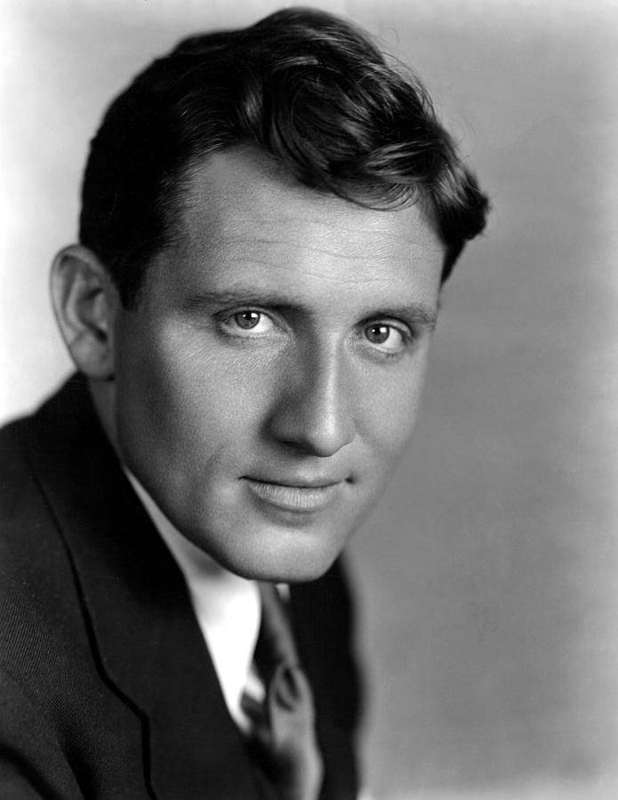 Spencer Tracy den amerikanske skuespiller posederede mod en grå baggrund. Wallpaper