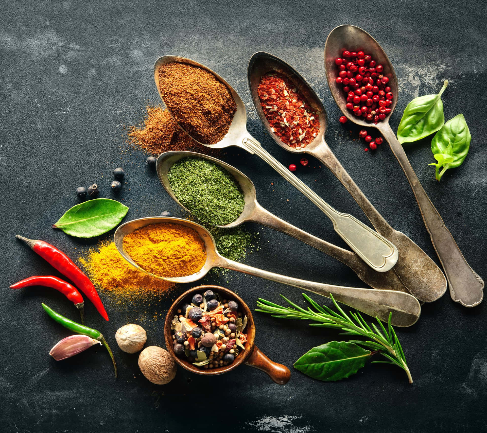 Spices And Herbs In Spoons On A Dark Background