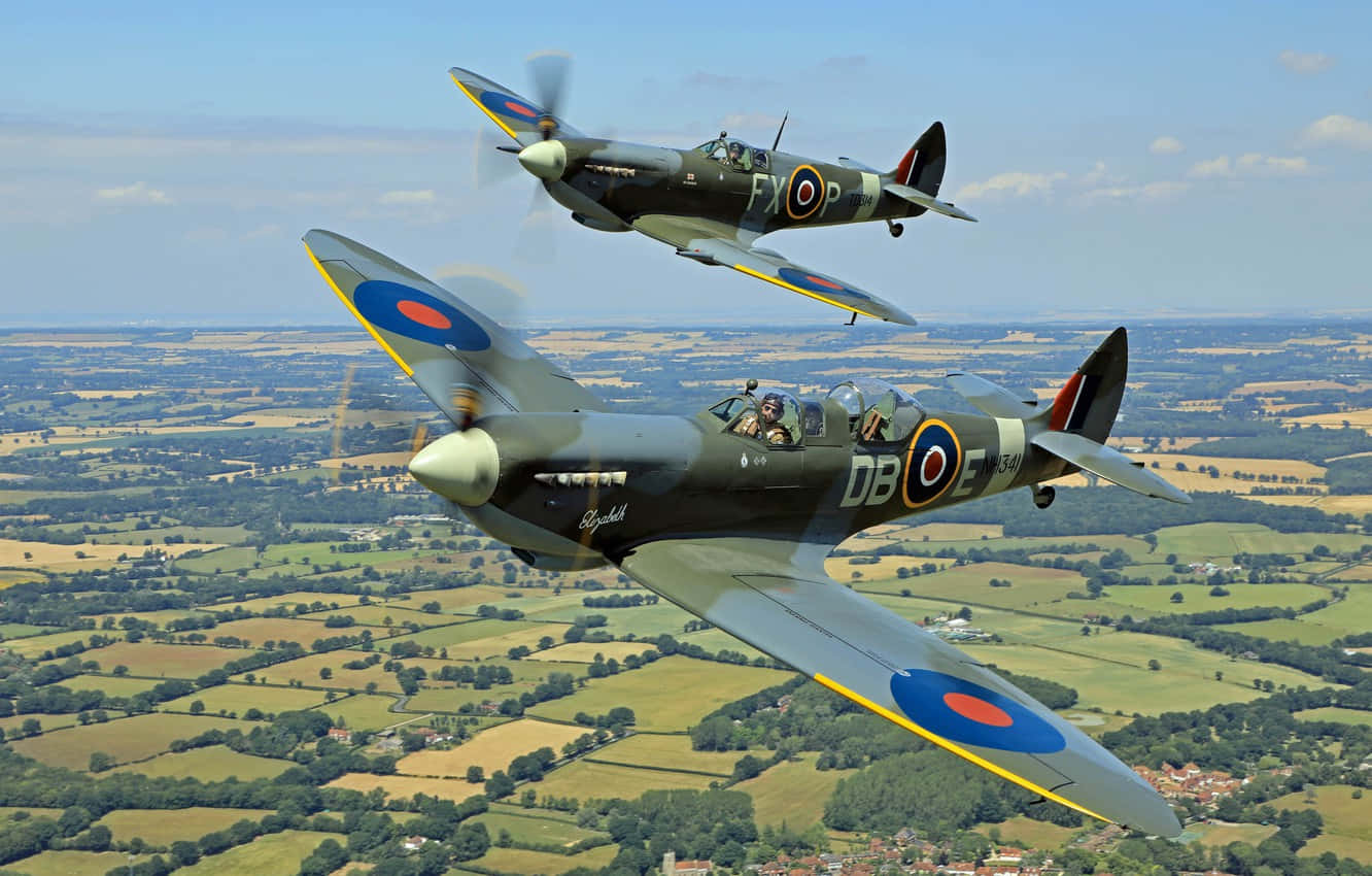 Two Old War Planes Flying Over A Field Wallpaper