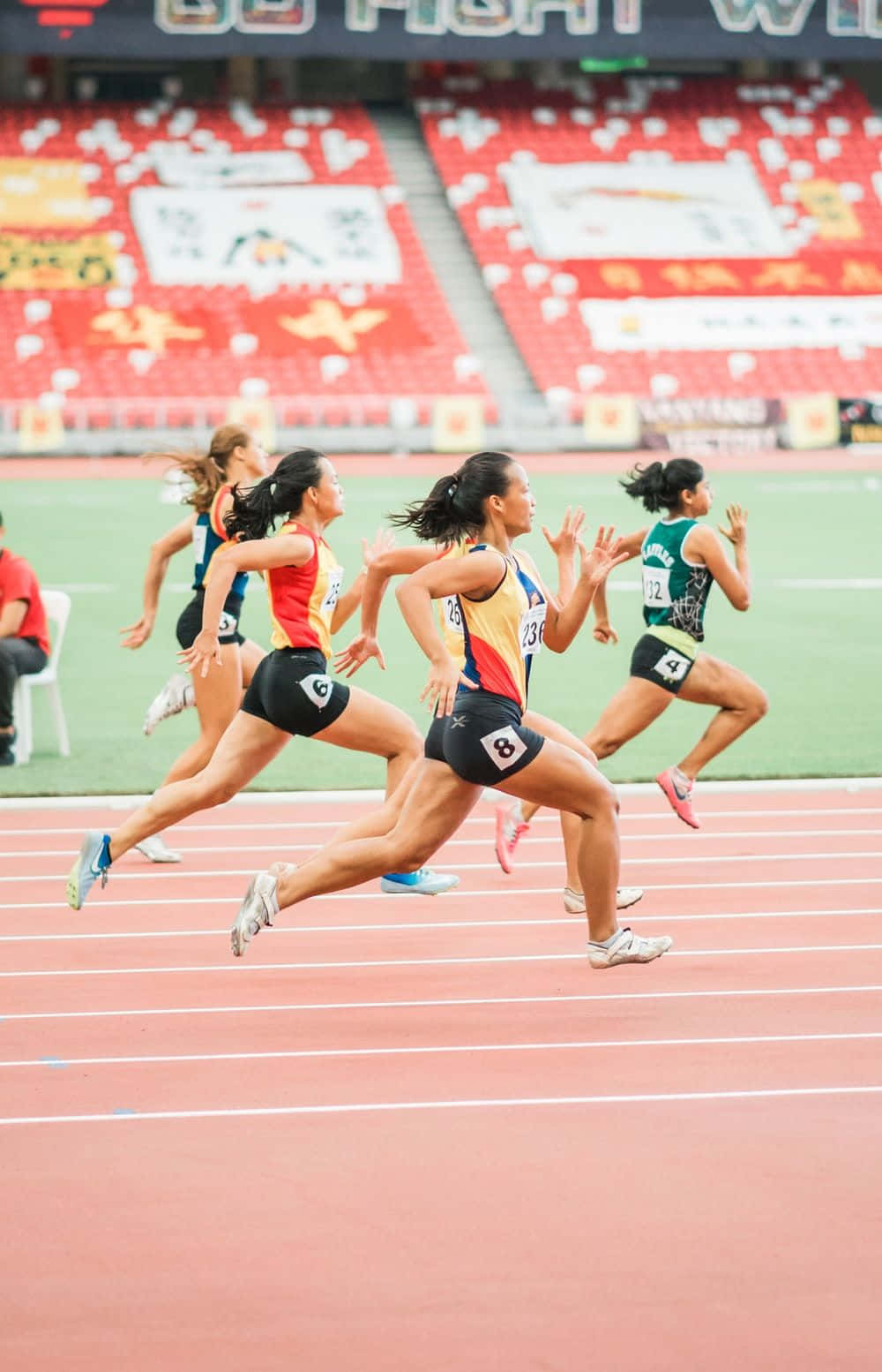 Ungrupo De Mujeres Corriendo En Una Pista En Un Estadio. Fondo de pantalla