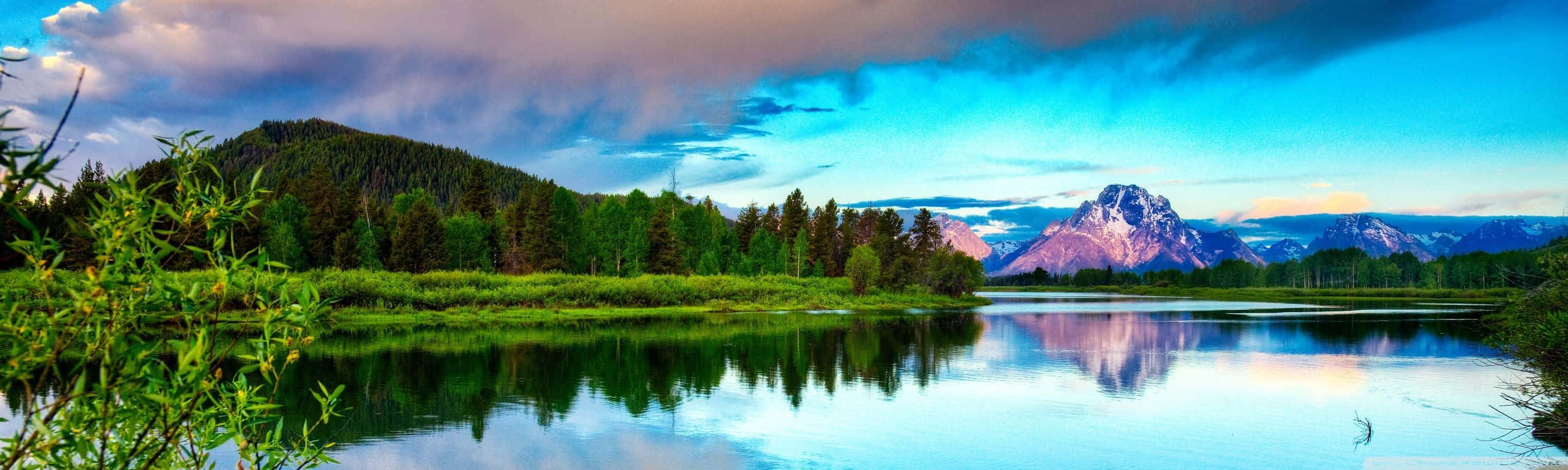 A Lake With Mountains And Clouds In The Background Wallpaper