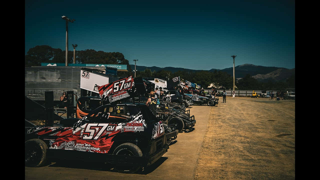 A Group Of Dirt Track Cars Parked In A Dirt Lot Wallpaper