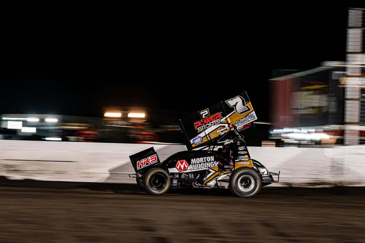 A Dirt Track Racer Driving At Night Wallpaper