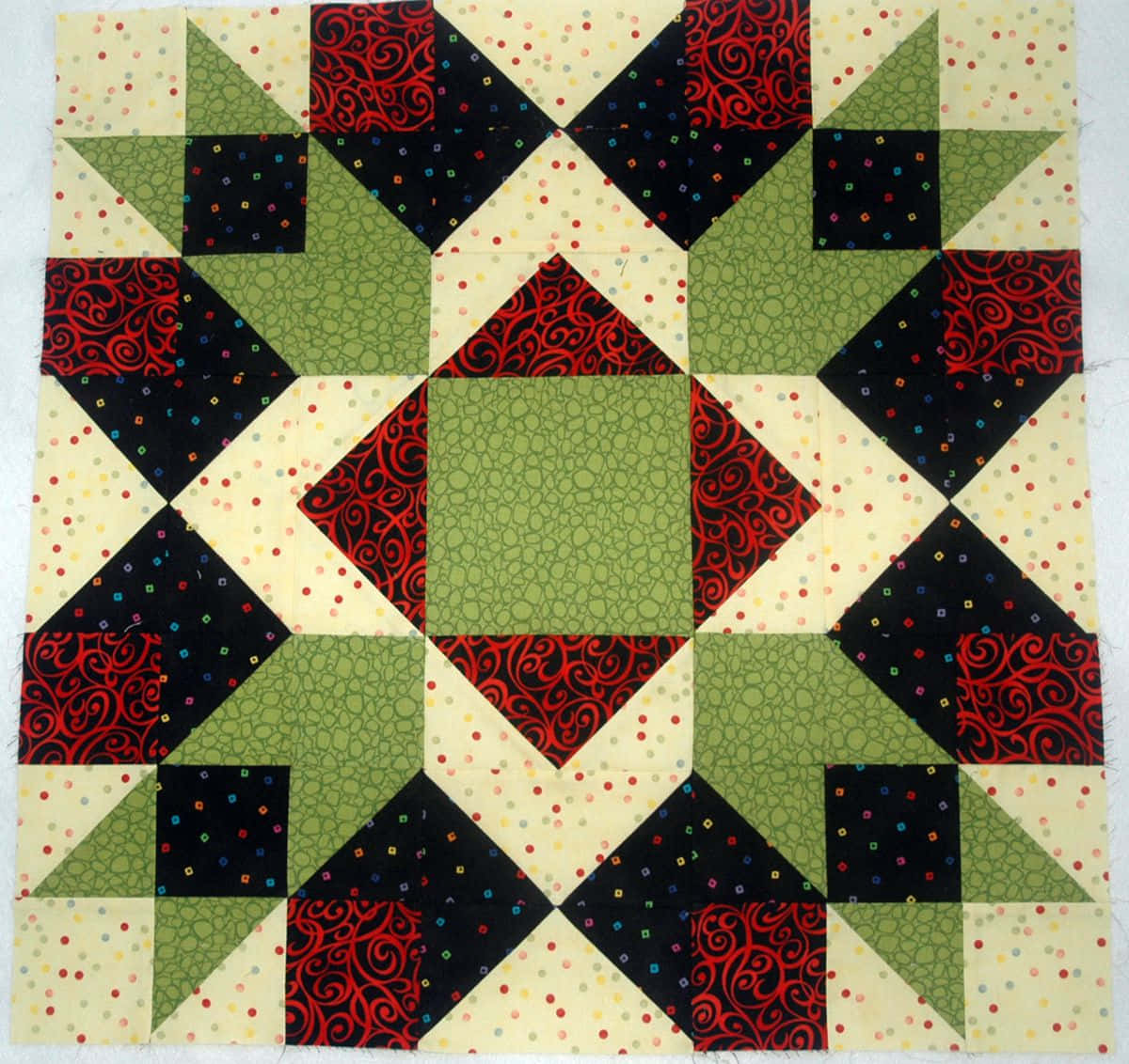 a quilt block with green, red and black squares