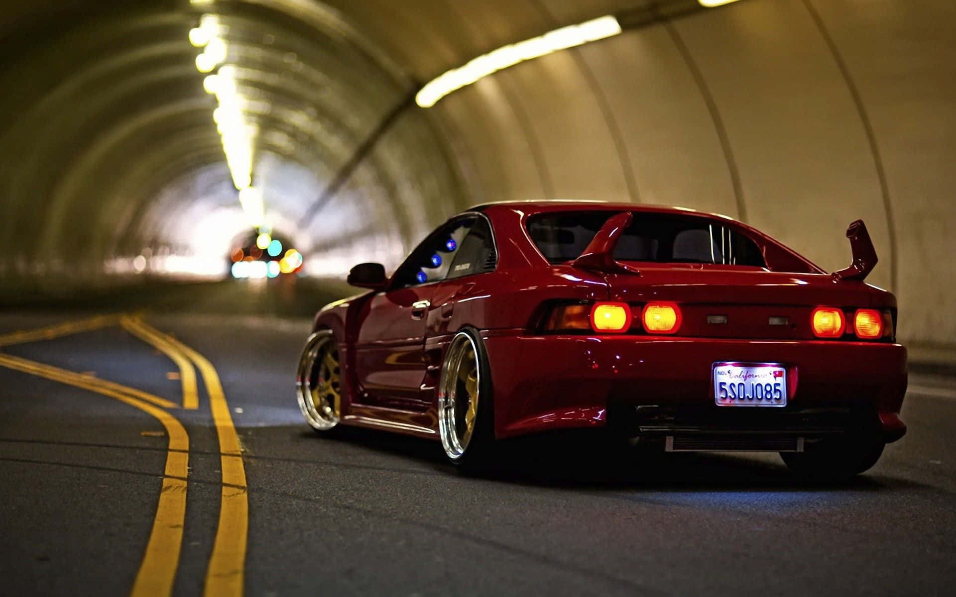 A Red Sports Car Driving Down A Tunnel Wallpaper