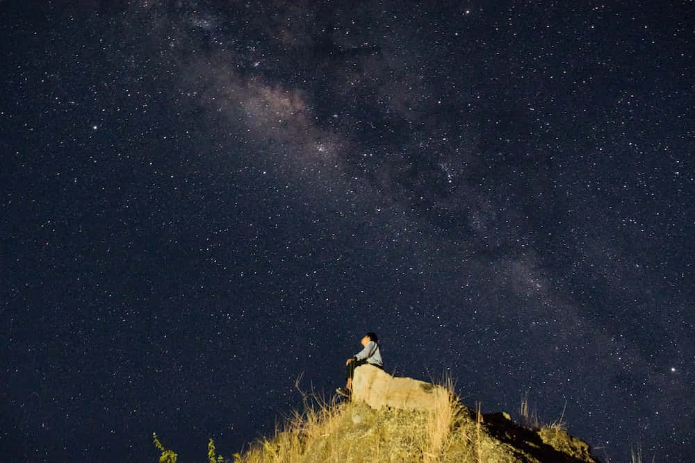 Umhomem Sentado Em Uma Rocha Olhando Para Cima Para A Via Láctea