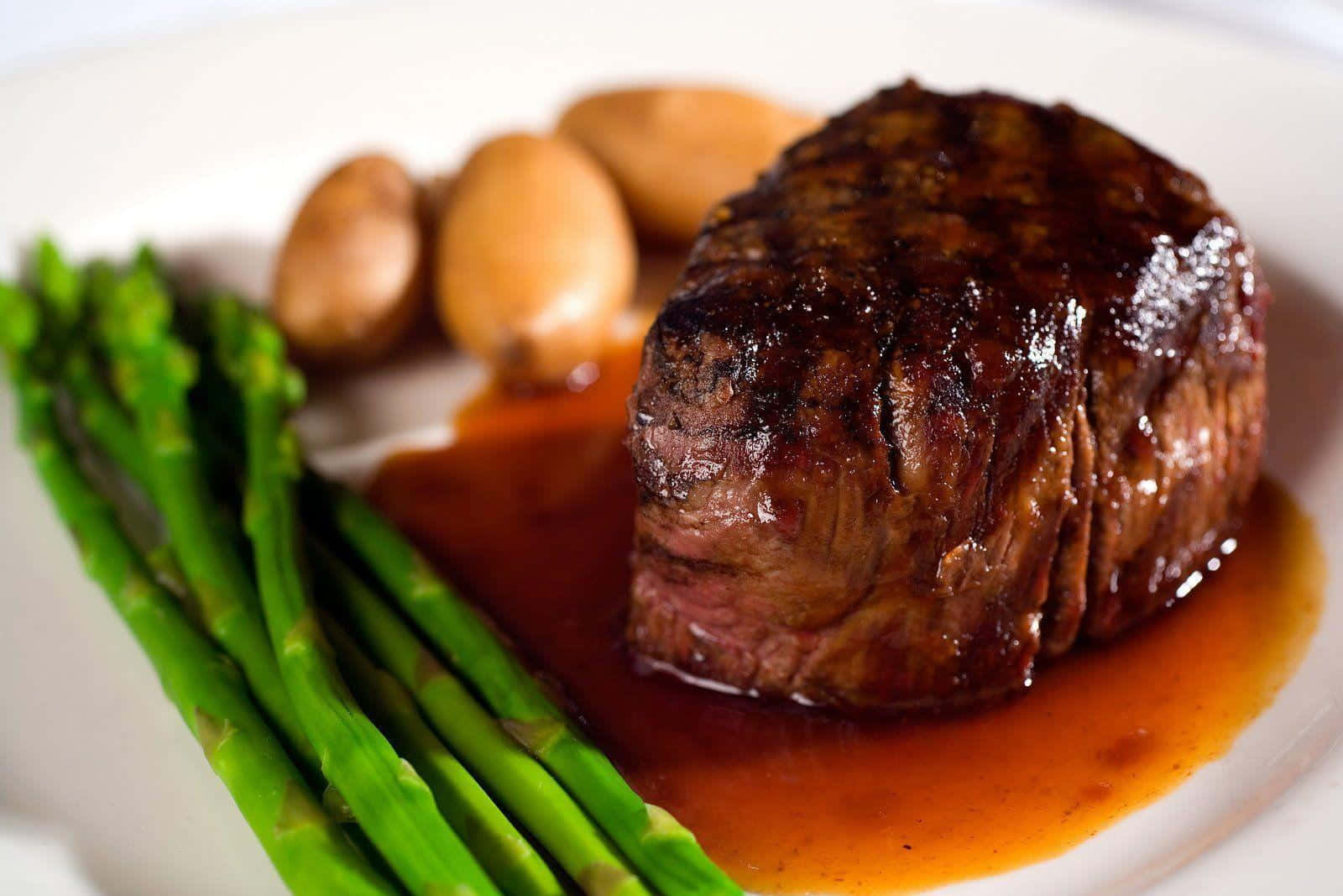 A Steak With Asparagus And Potatoes On A Plate